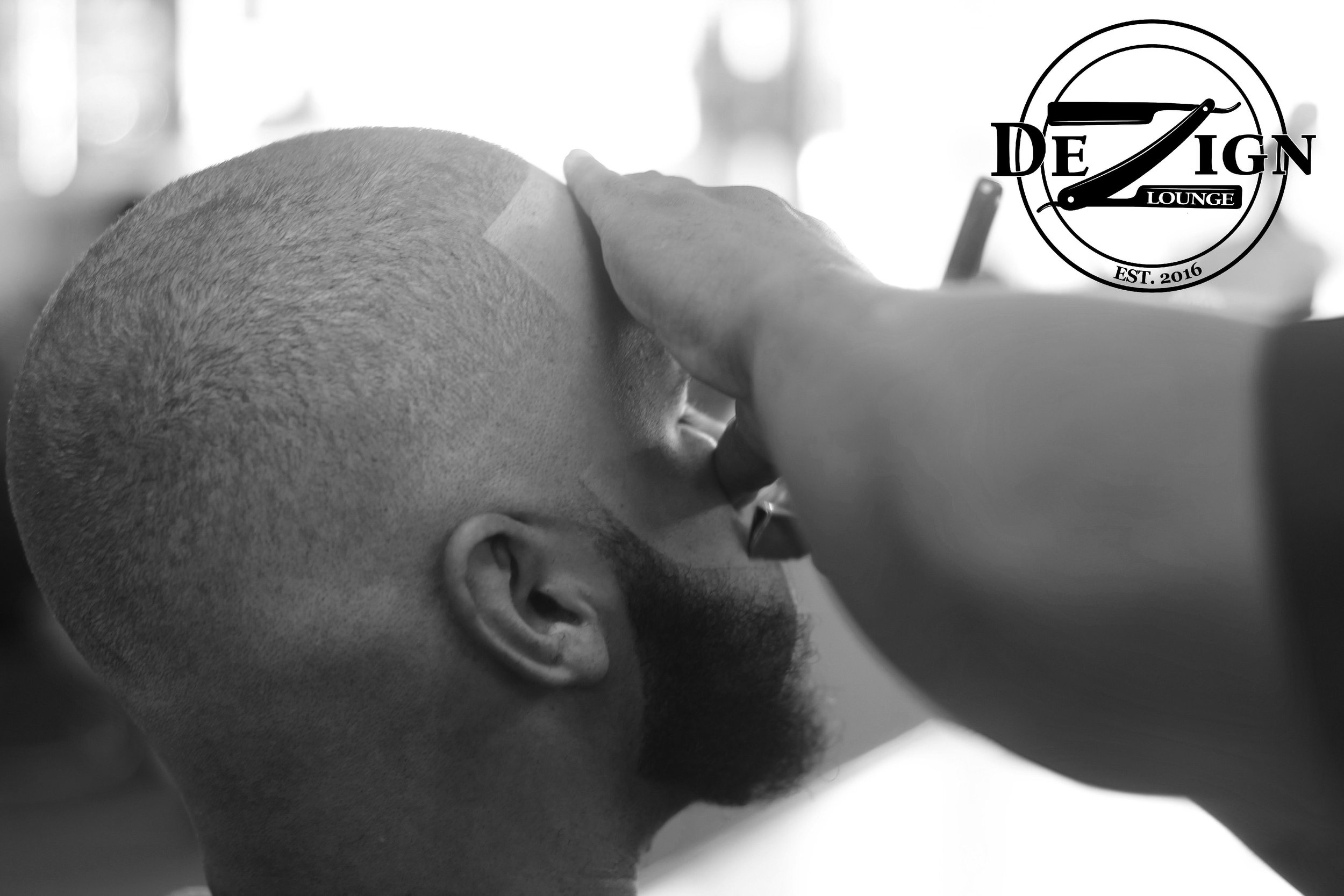 A man getting a close shave at a barbershop, with a barber applying shaving cream or lotion to his face.
