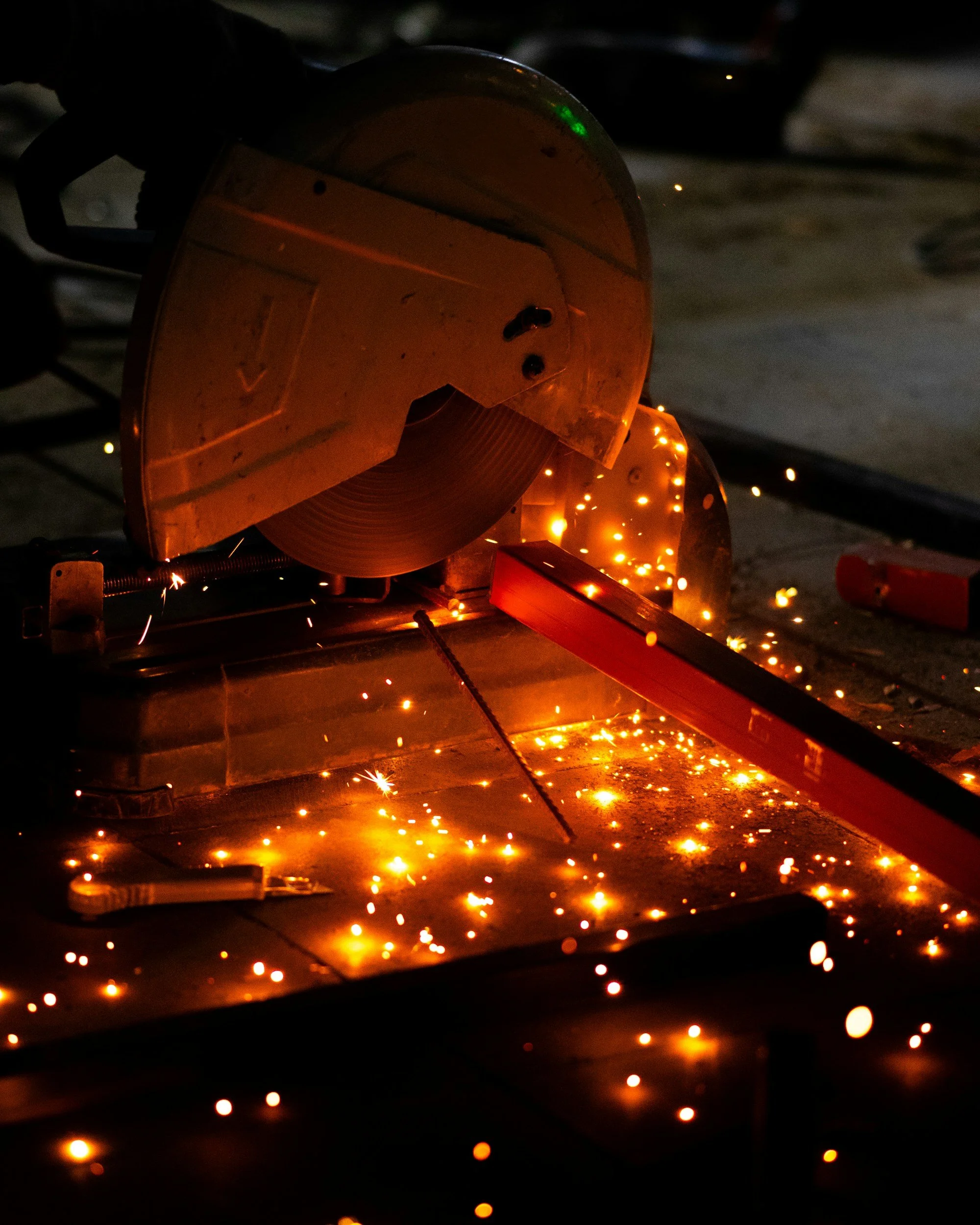 A metal circular saw blade with sparks flying around during cutting or grinding, set in a dark workshop environment.