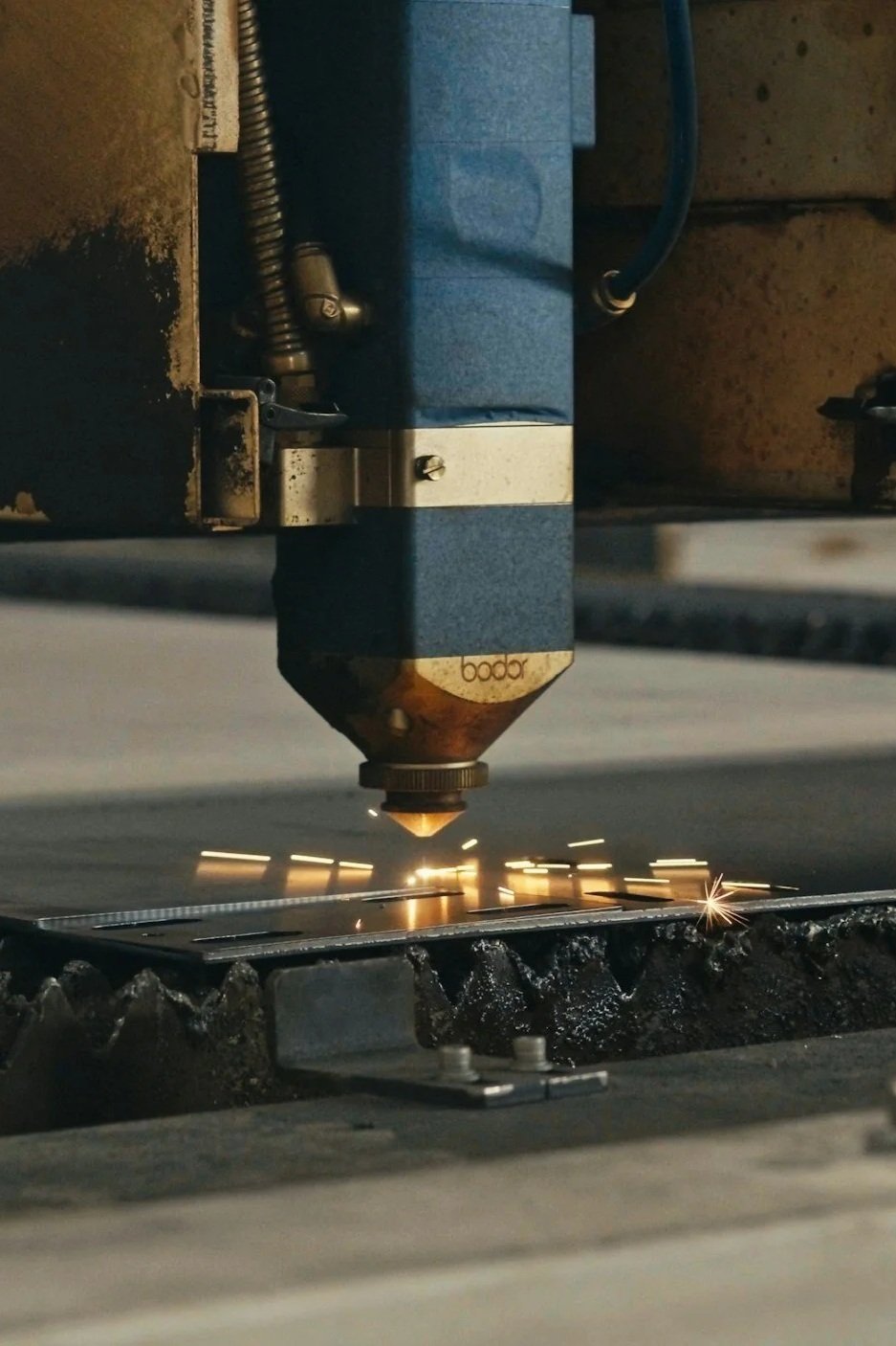 A CNC laser cutter engraving or cutting metal with sparks flying.
