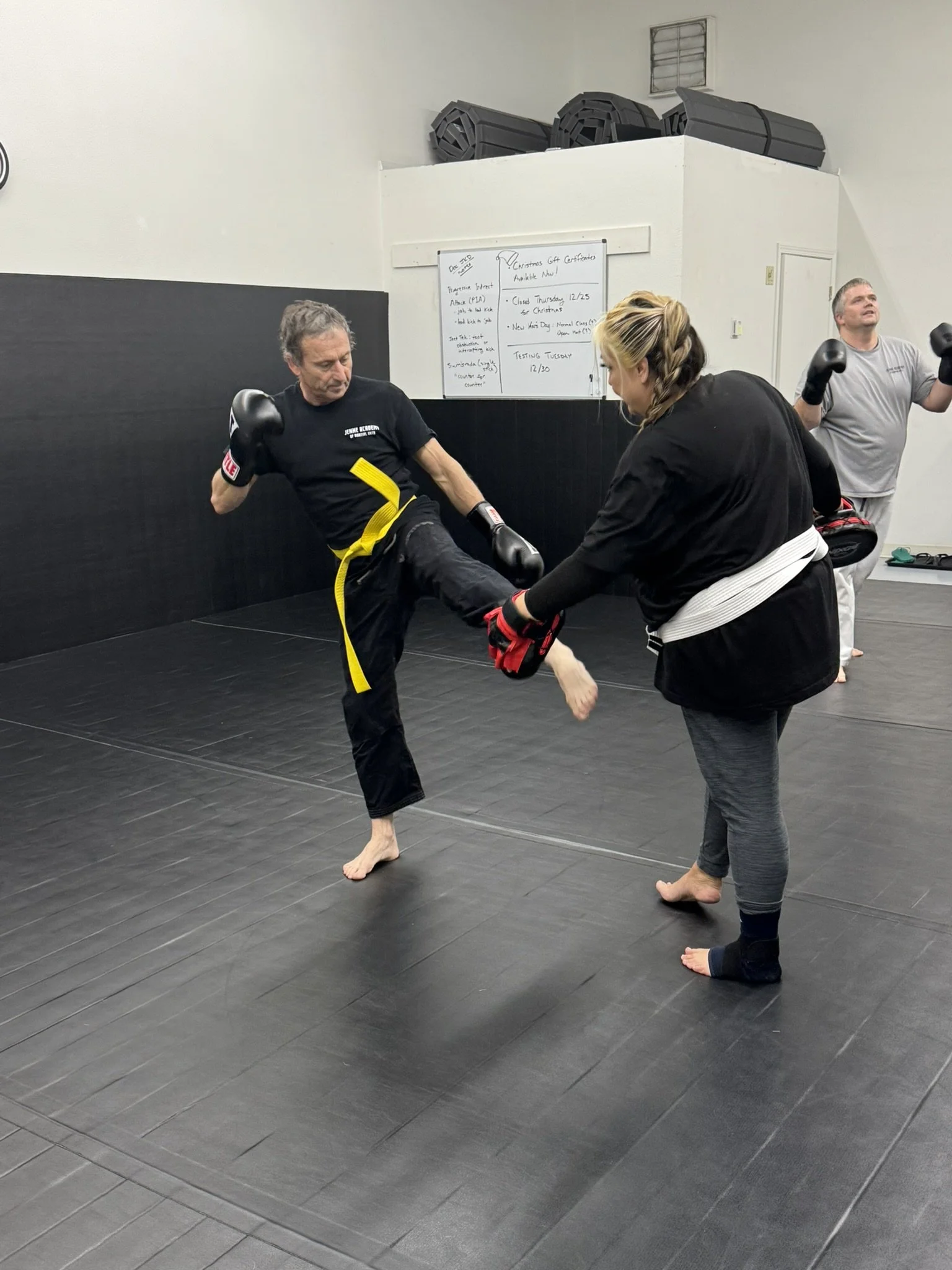 Students practicing a kick with a partner holding training pads.