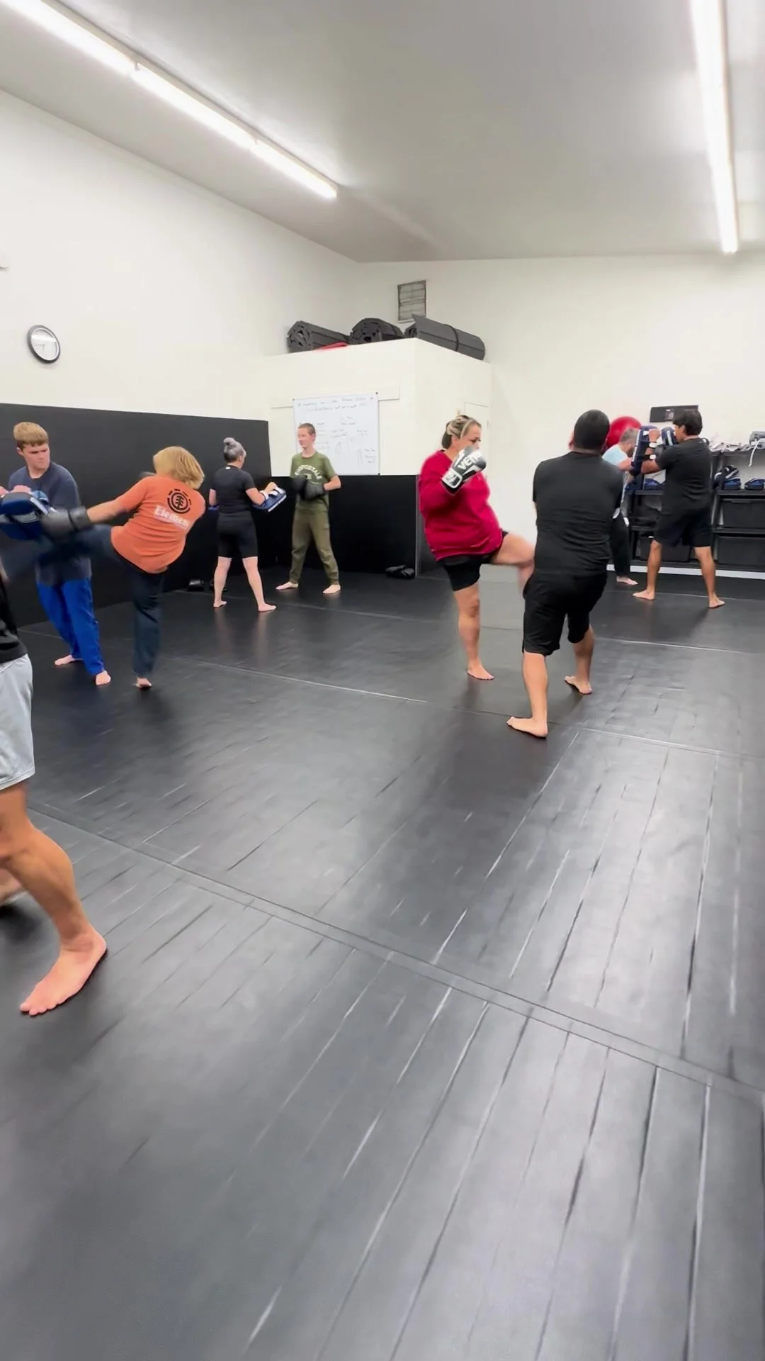 Students practicing kicks and pad work during a kickboxing class.