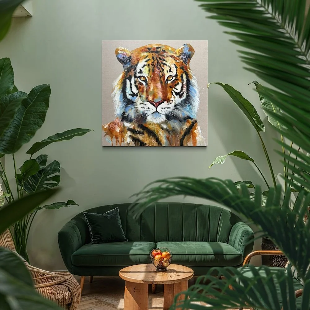 Tiger painting by Louise Luton in A cozy living room with a green velvet sofa, a wooden coffee table with a bowl of fruit, and large green plants