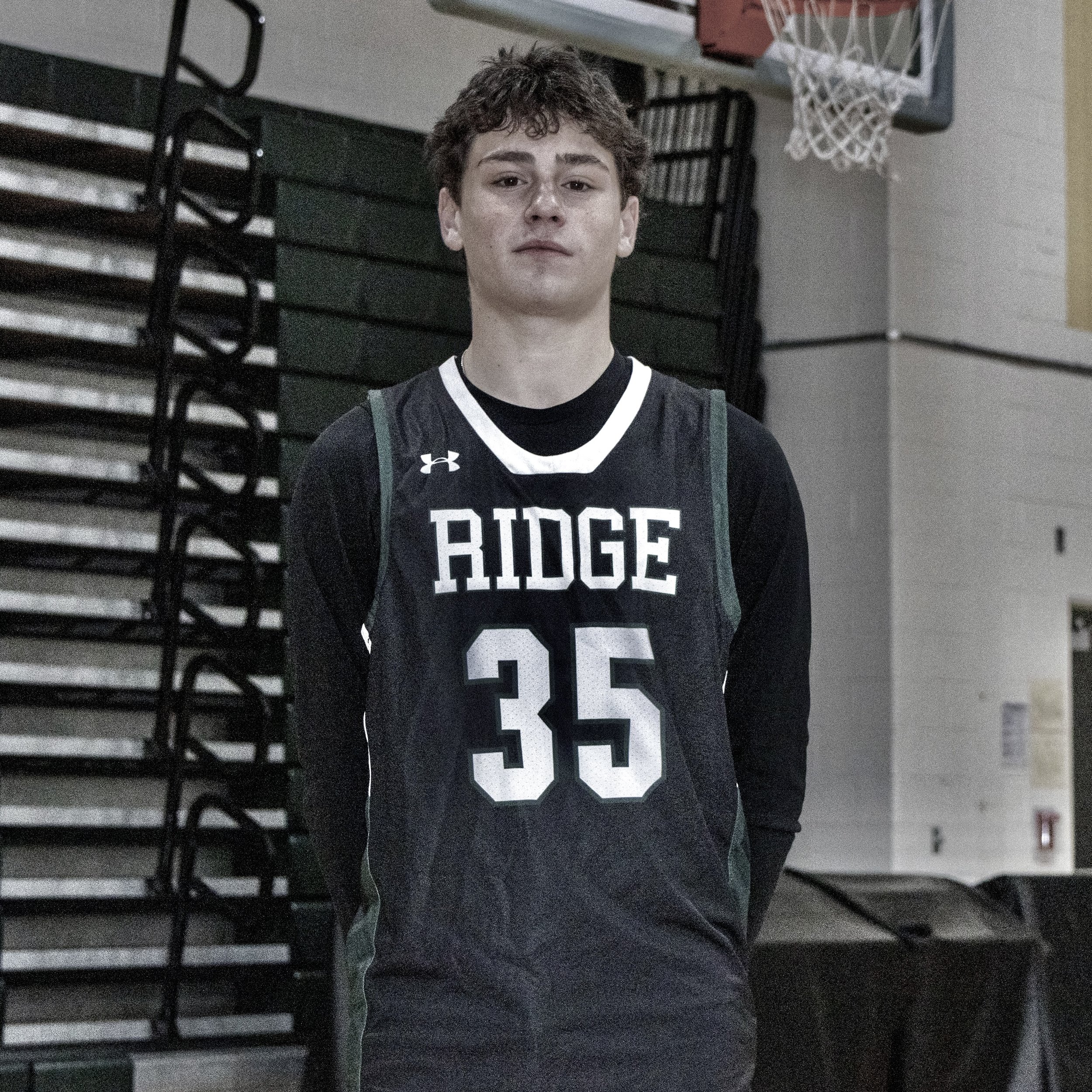 A young male basketball player wearing a black jersey with the text 'Ridge' and the number 35 stands in an indoor gymnasium.