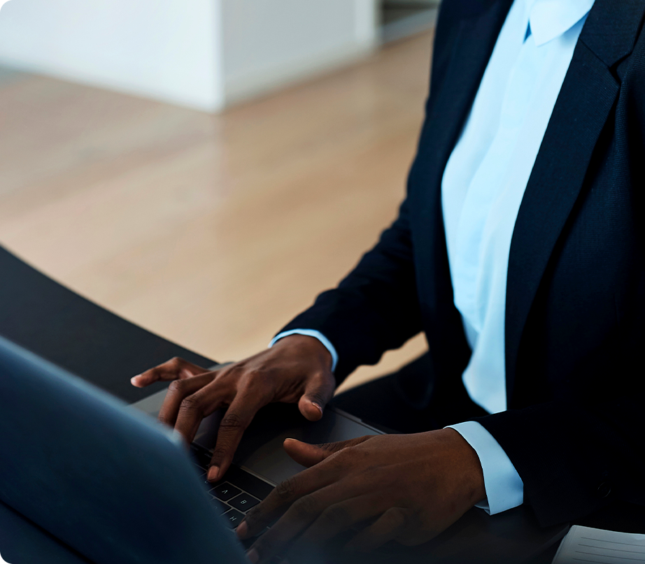 Person in business suit working on a laptop at a desk.