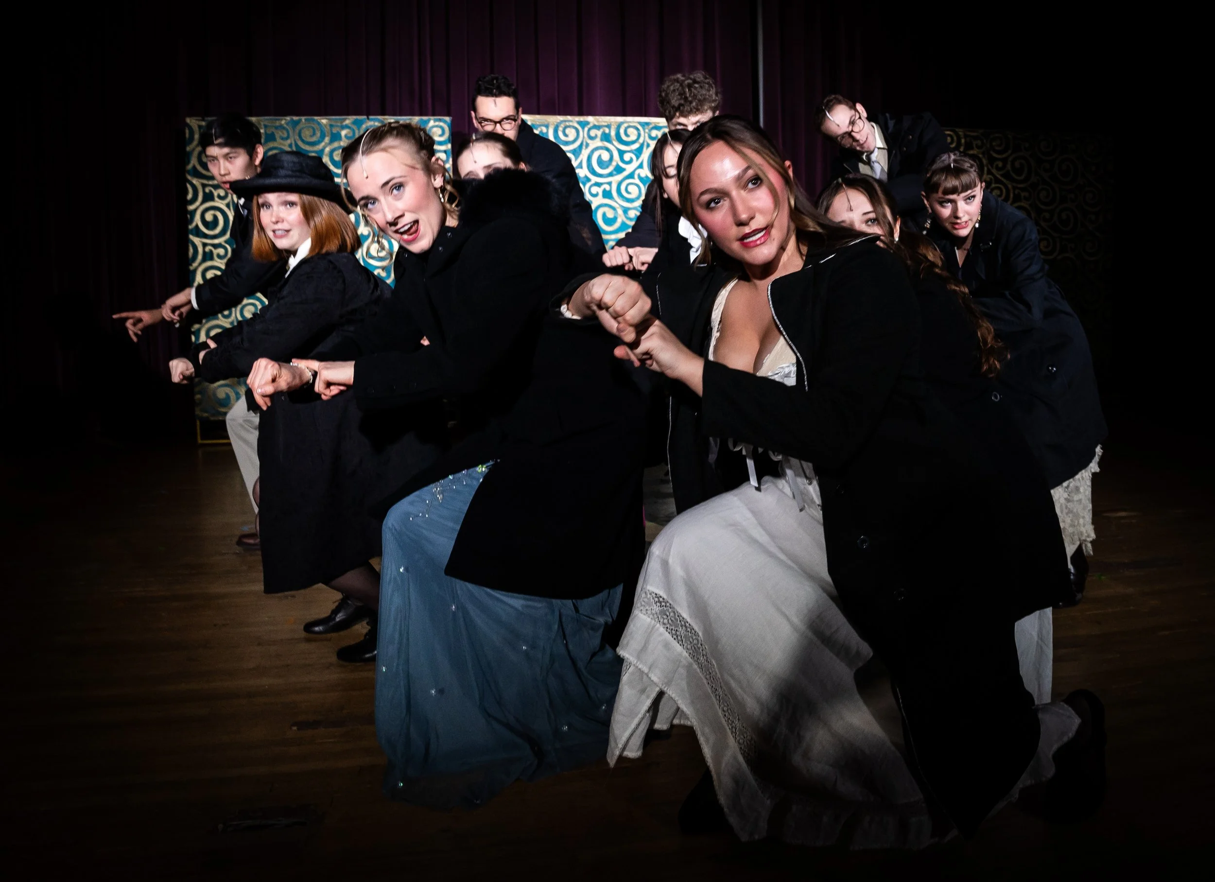 The cast of A Gentleman's Guide to Love and Murder musical performing on stage in costumes, striking a dramatic pose with intense expressions.