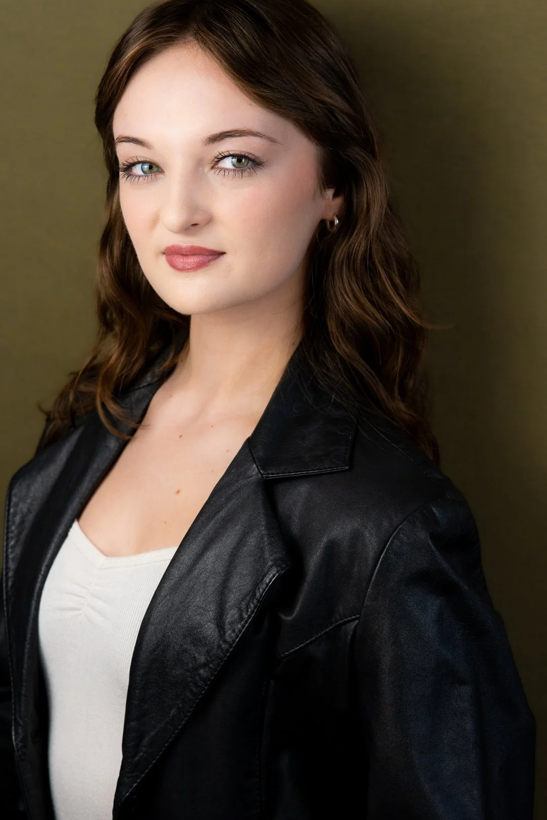 Headshot of Sarah Novak with brown hair, blue eyes, wearing a black leather jacket over a white top, against a plain background.