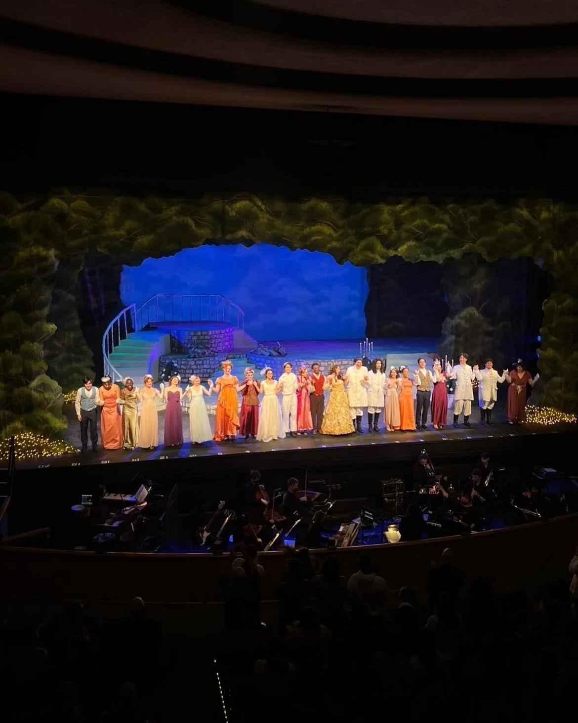 The cast of a theatrical play or musical standing in a line on stage at the end of the performance, holding hands and bowing to the audience.