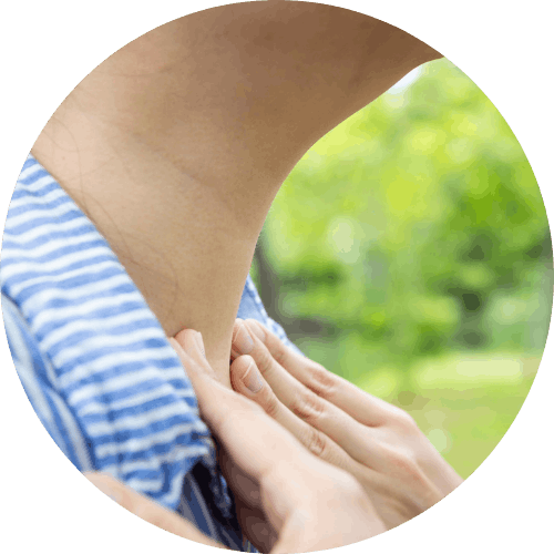 Person performing a neck stretch outdoors with a hand on the collar of a striped shirt, green blurred background