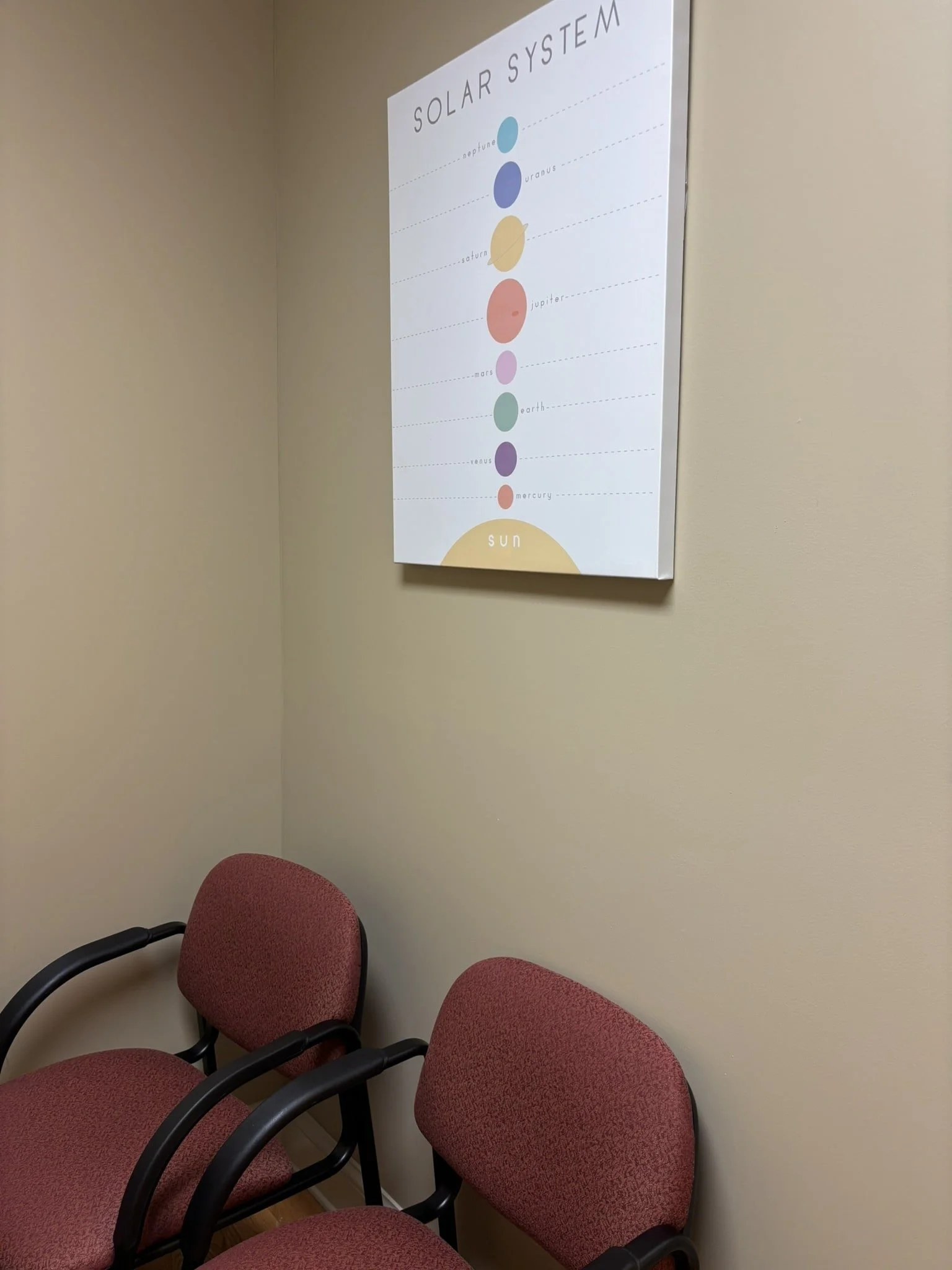 Chairs in a waiting room with a poster of the solar system on the wall