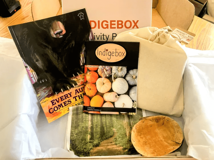 Indigebox gift box filled with art books, a canvas tote bag, forest artwork, and a wooden slice