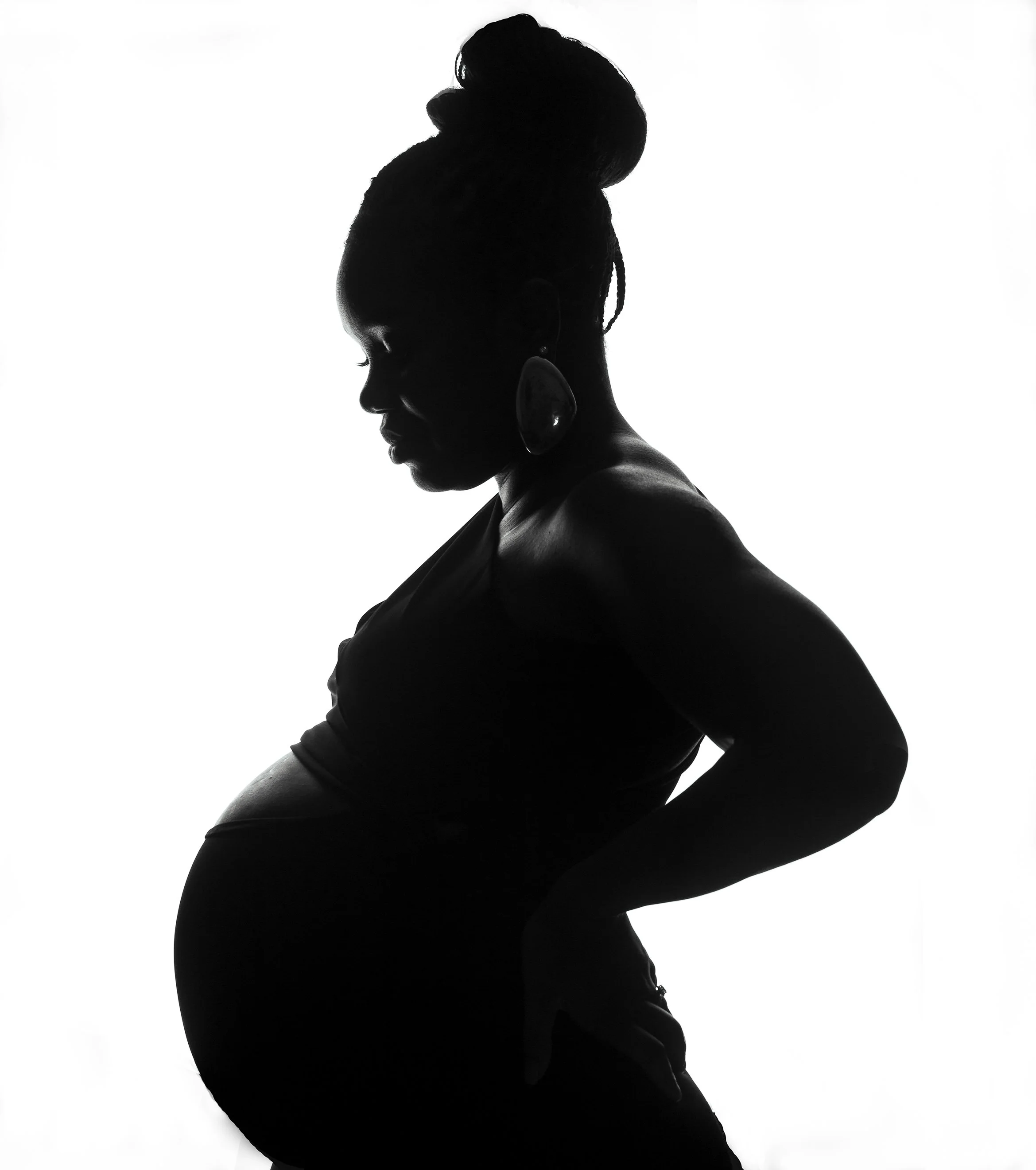 Silhouette of a pregnant woman with her head bowed, standing with one hand on her hip and the other on her belly, against a white background.