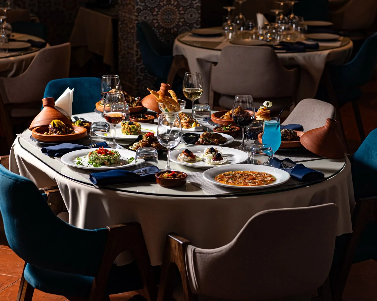 Table dressée avec divers plats gastronomiques, vins, et décor élégant dans un restaurant