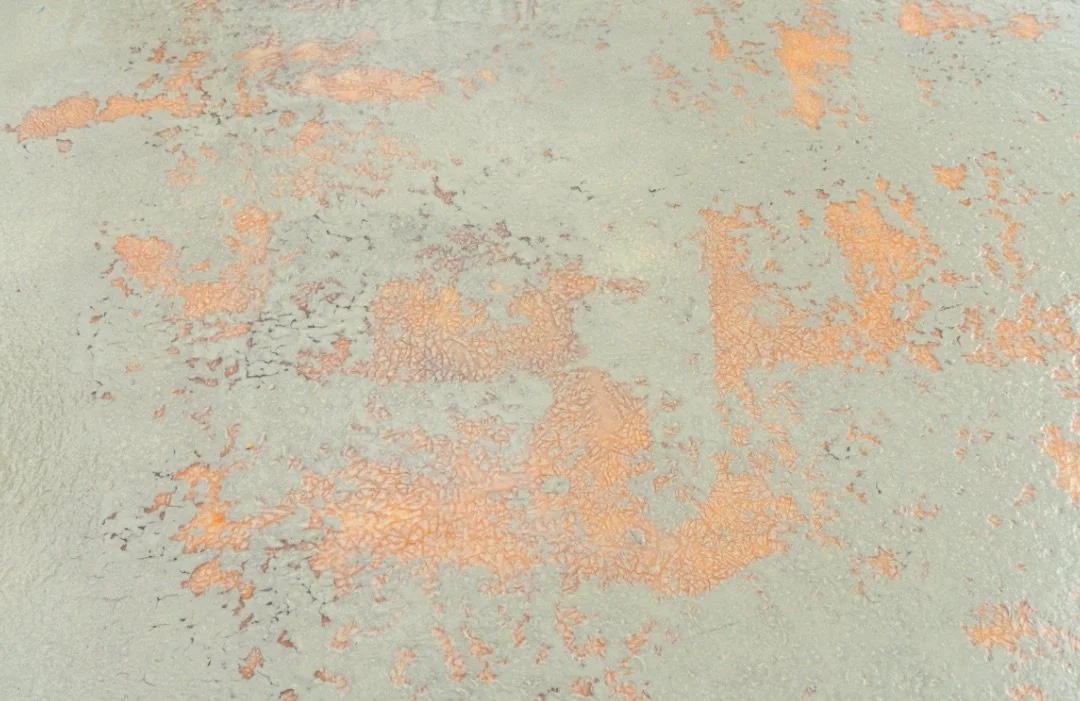 a close-up of a weathered wall with peeling paint in shades of orange and light green