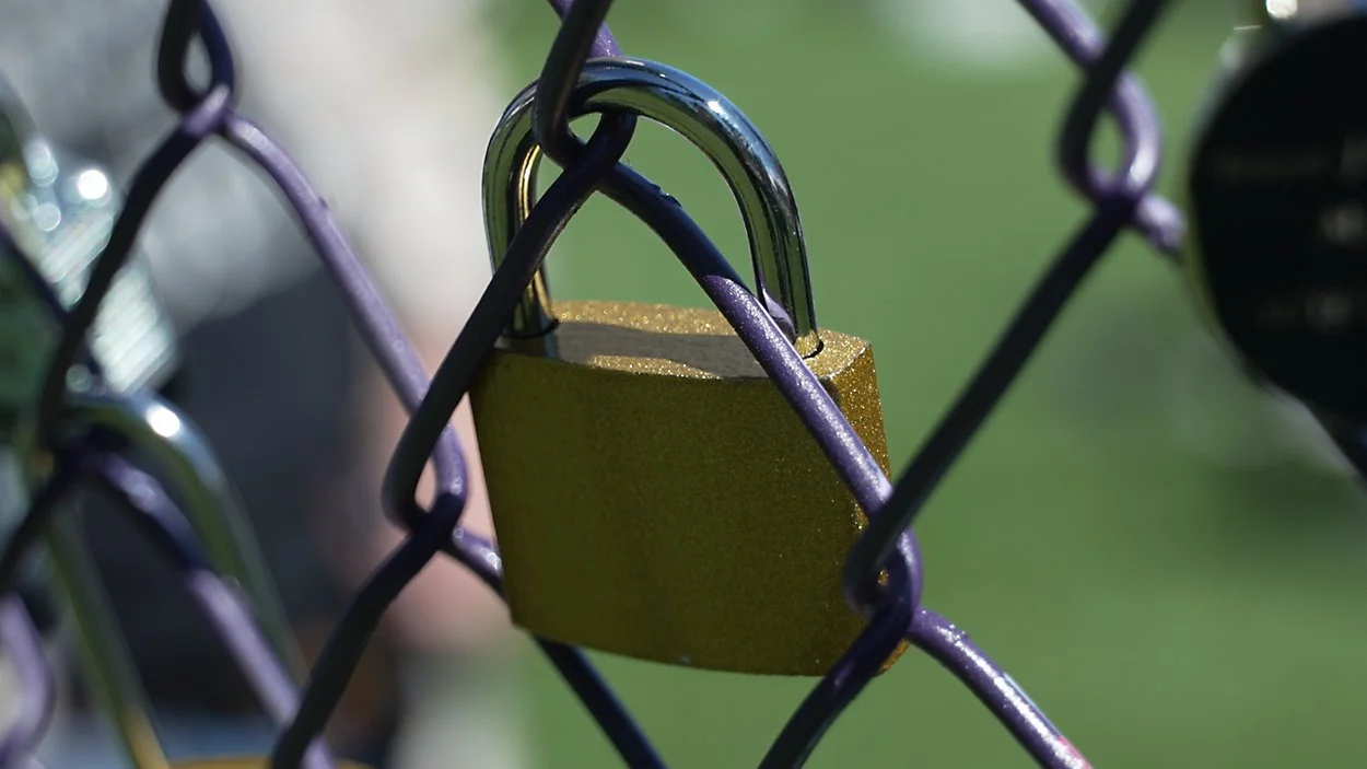 Gold padlock attached to a purple chain-link fence for International Overdose Awareness Day.