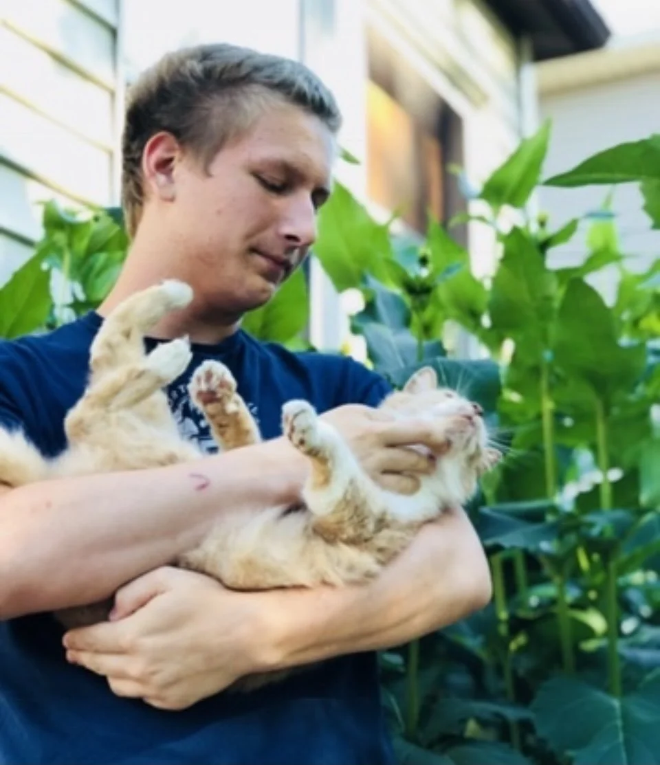 Miles Gamez holding an orange-and-white cat outdoors.