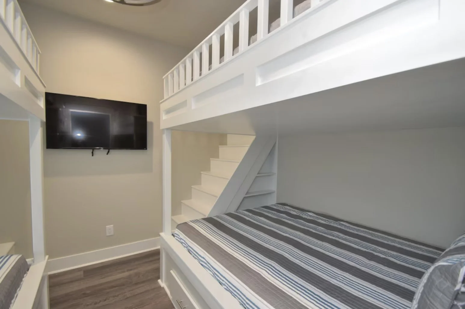 Bedroom with a bunk bed, a wall-mounted TV, and beige walls.