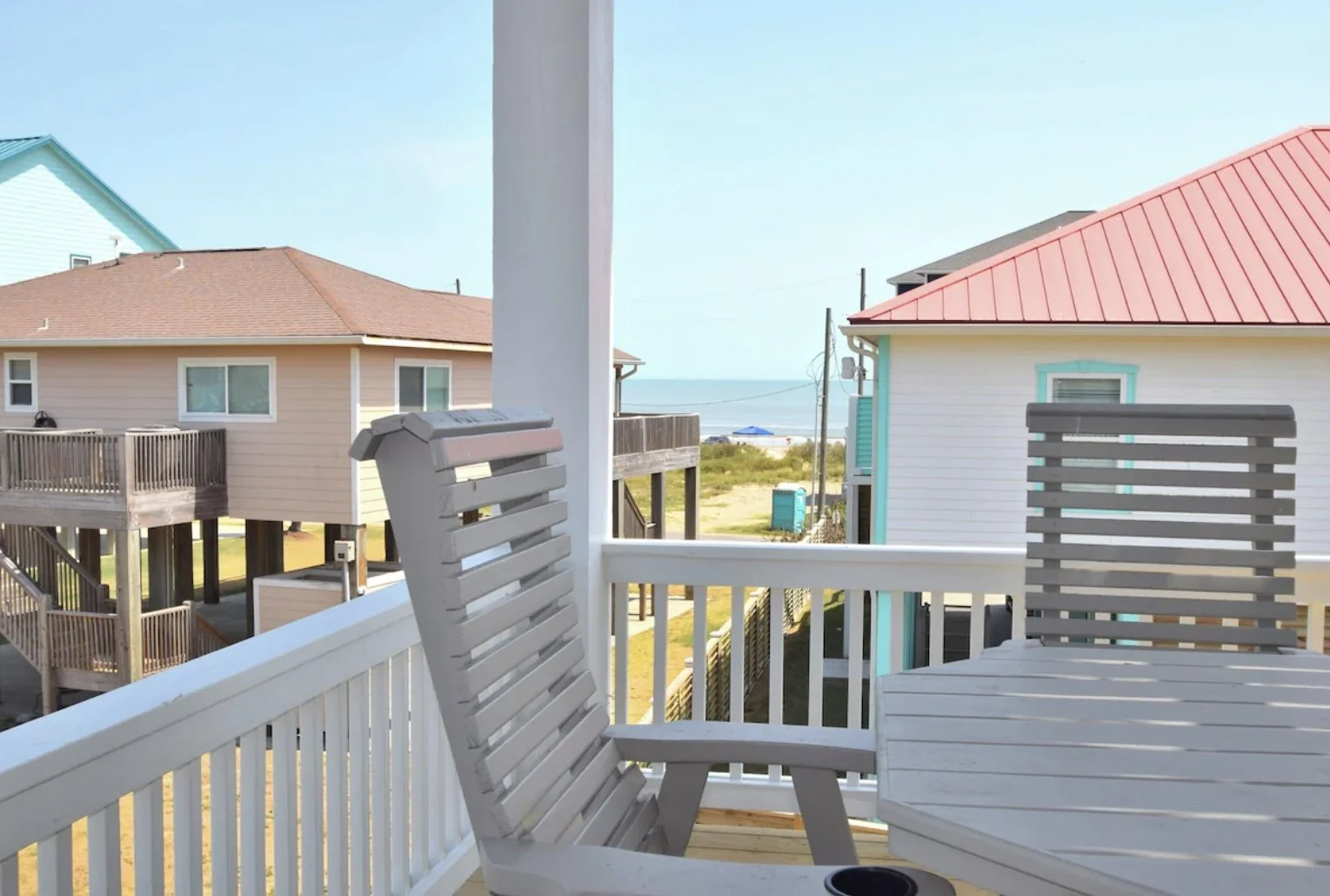 View from a porch overlooking beach houses with a view of the ocean and beach