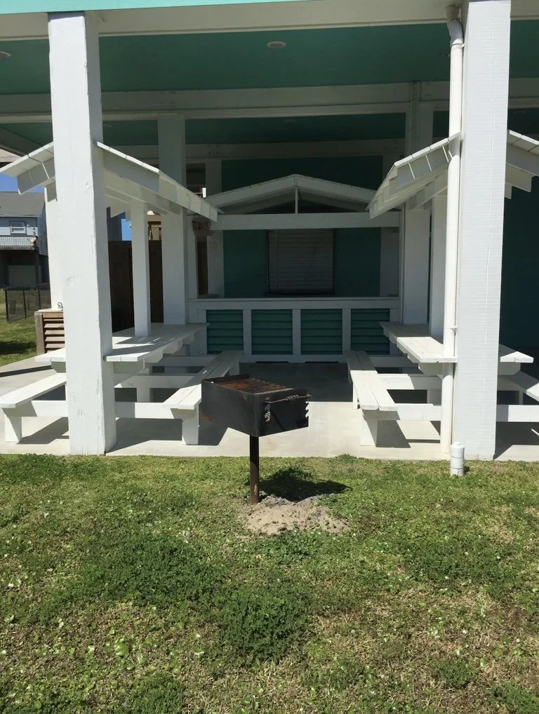 Backyard outdoor patio with built-in benches and a grill in front