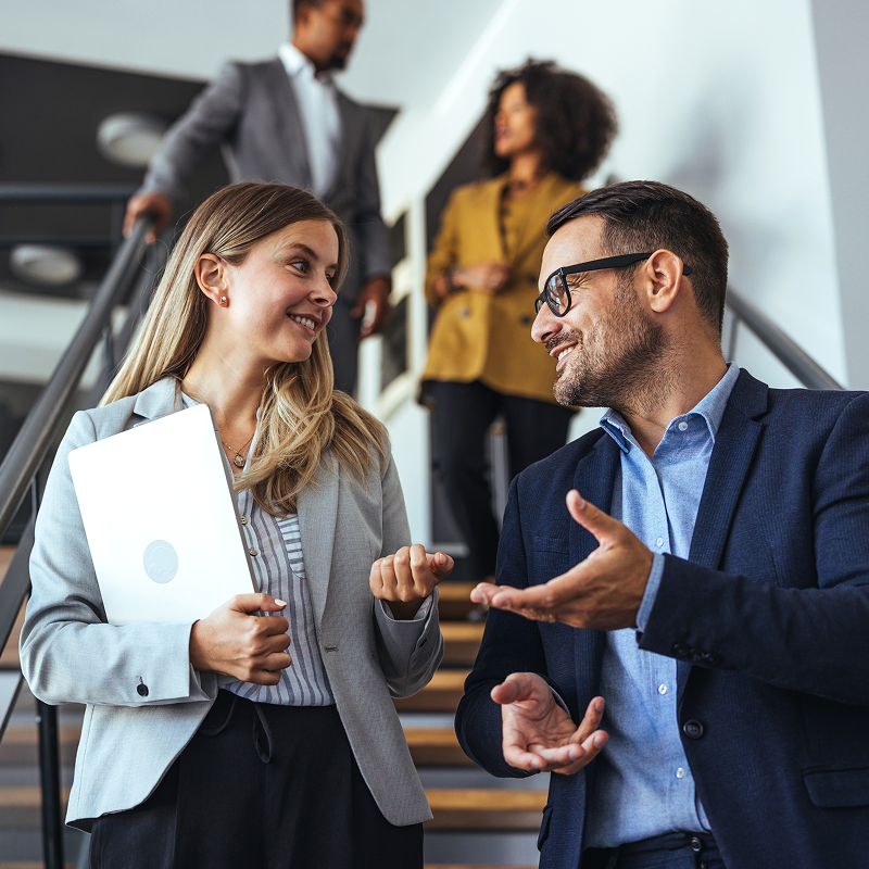 Business professionals having a discussion in an industrial space with whiteboard and charts.
