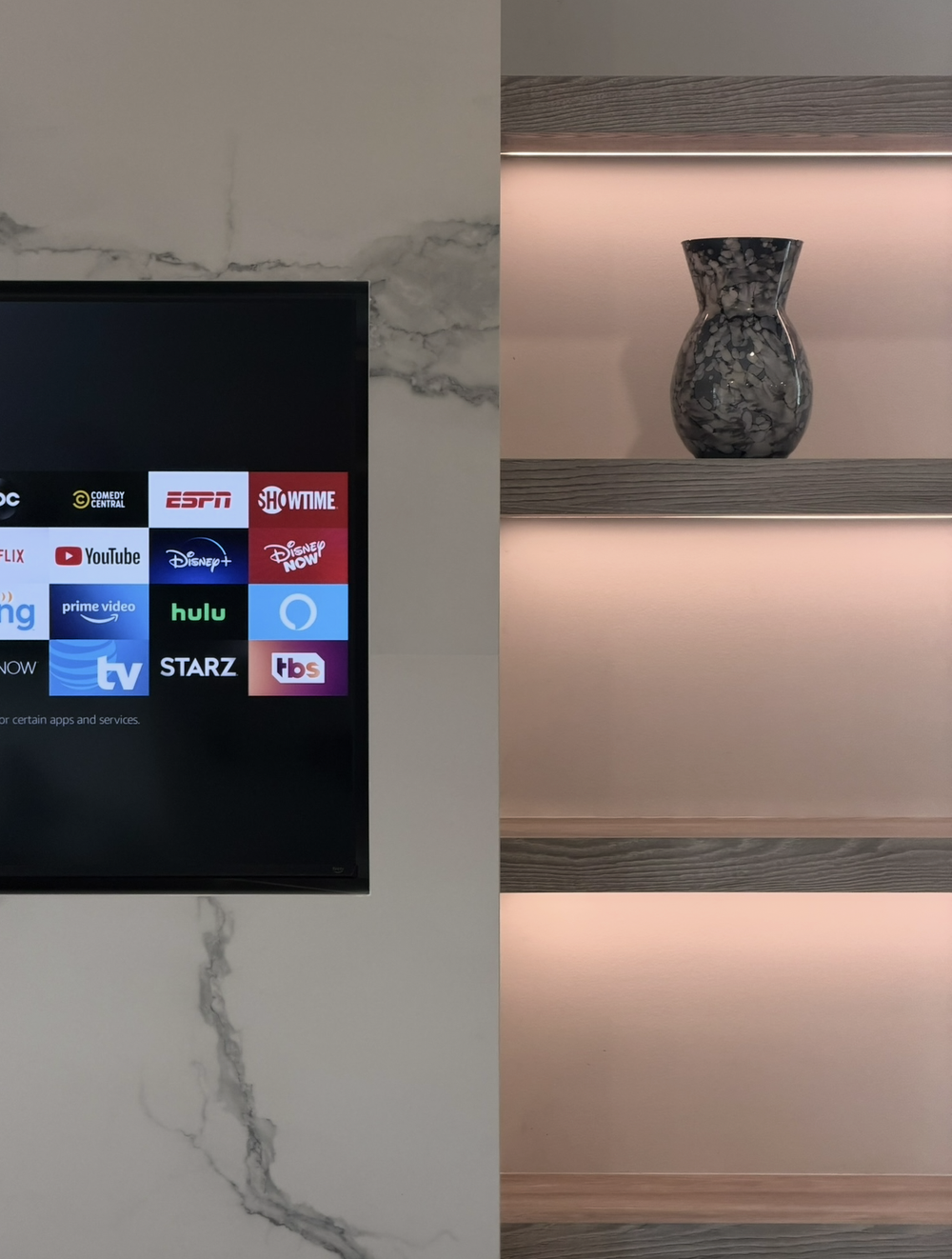 Close view of pale woodgrain display shelves with integrated lighting beside the media wall television
