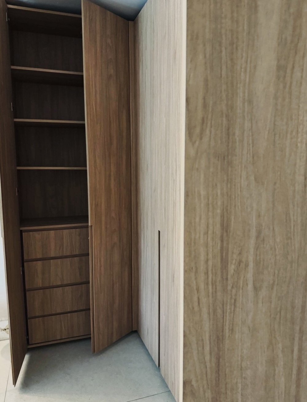 Open Miami Beach wardrobe showing shelves and stacked drawers beside woodgrain doors with recessed pulls