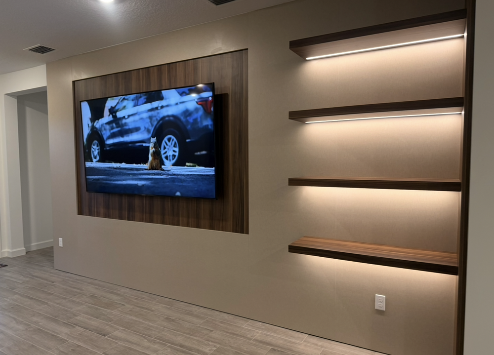 Woodgrain television back panel beside four floating shelves with integrated lighting and a matching vertical side panel
