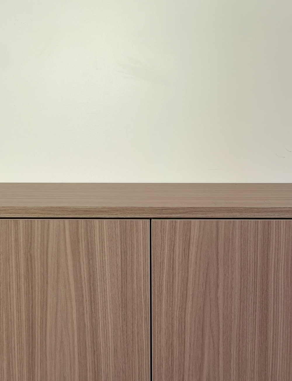 Close view of light woodgrain media console fronts, the top surface and the narrow reveal between doors