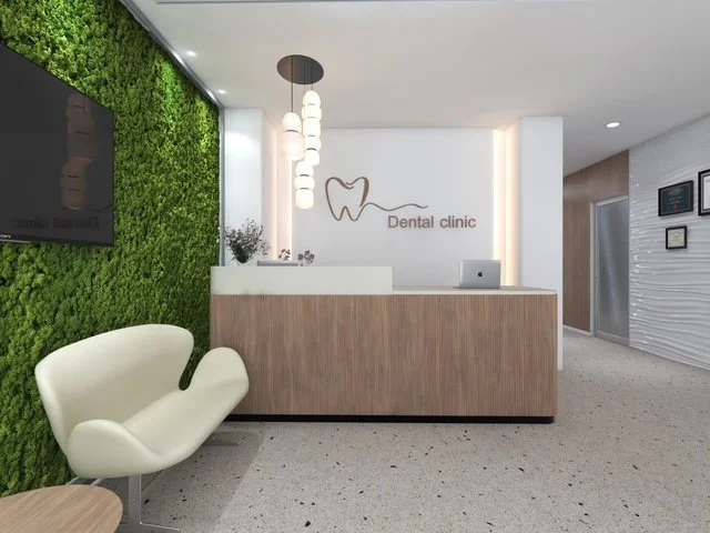 Modern dental clinic reception area with a green moss wall, white and wooden decor, a white chair, and dental clinic signage.