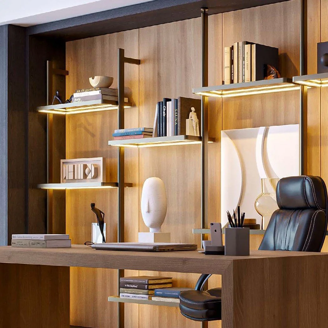 A modern office with a wooden desk and black leather chair, a decorative sculpture, and a wall-mounted bookshelf with illuminated shelves filled with books and decorative objects.