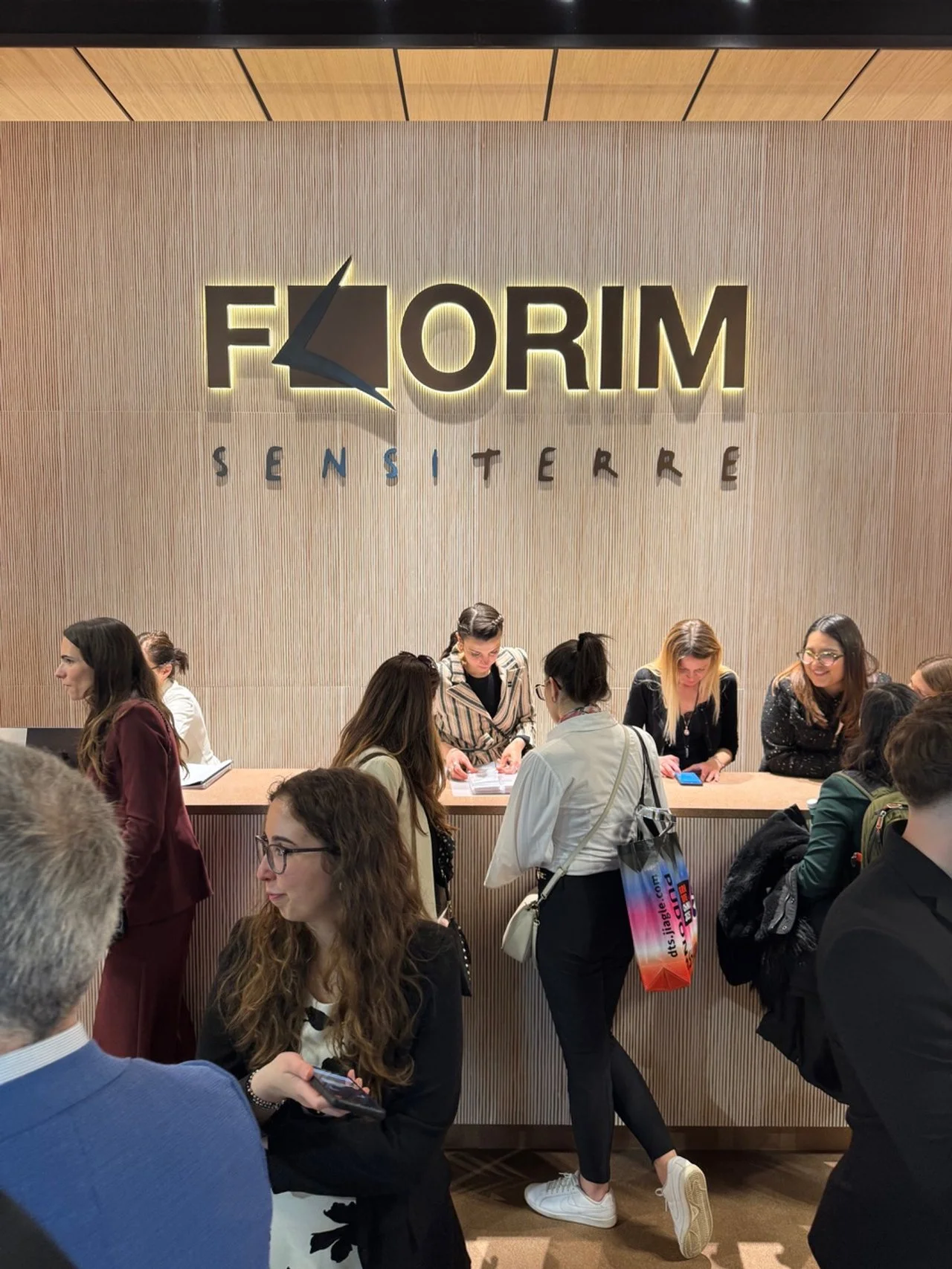 Reception area at FORM Sensitere, with multiple people checking in or talking to staff behind the counter, in a modern space.