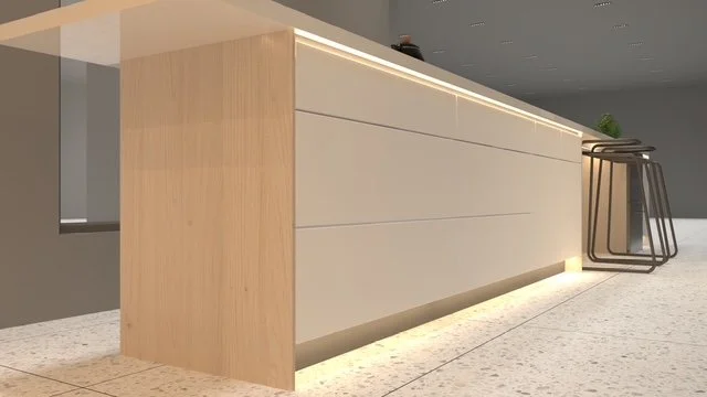 Modern kitchen island with a light wood finish and built-in lighting at the base, with bar stools stacked nearby.