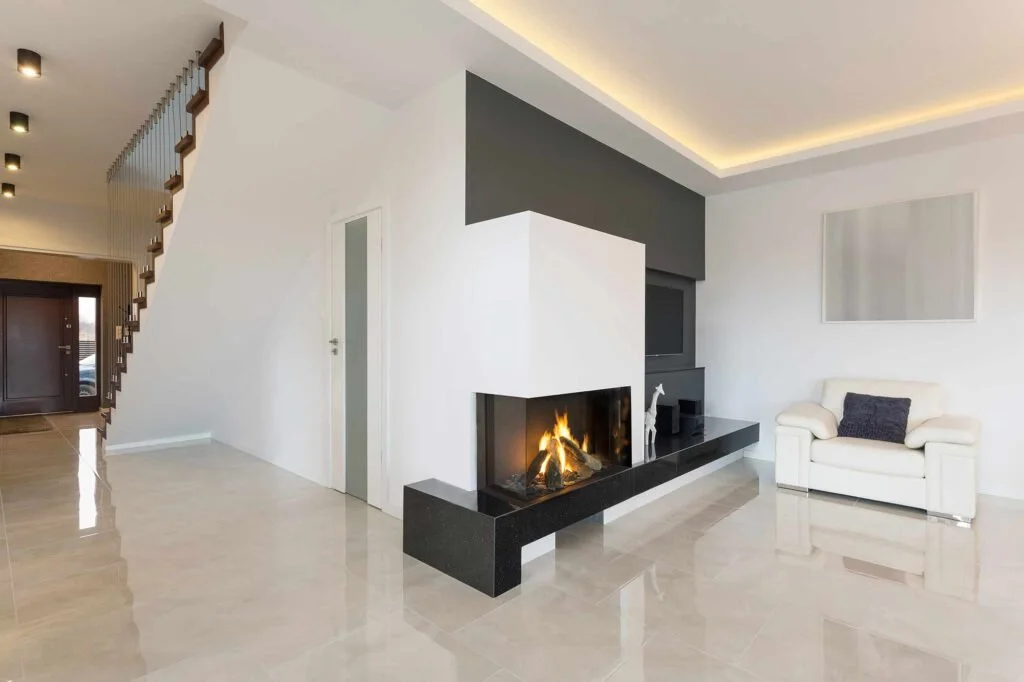 Modern living room with white walls, a fireplace, a white armchair, and decorative items.