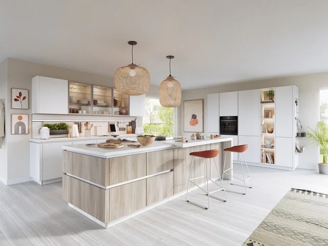 Modern white and wood kitchen with island, two orange barstools, pendant lights, and open shelving.