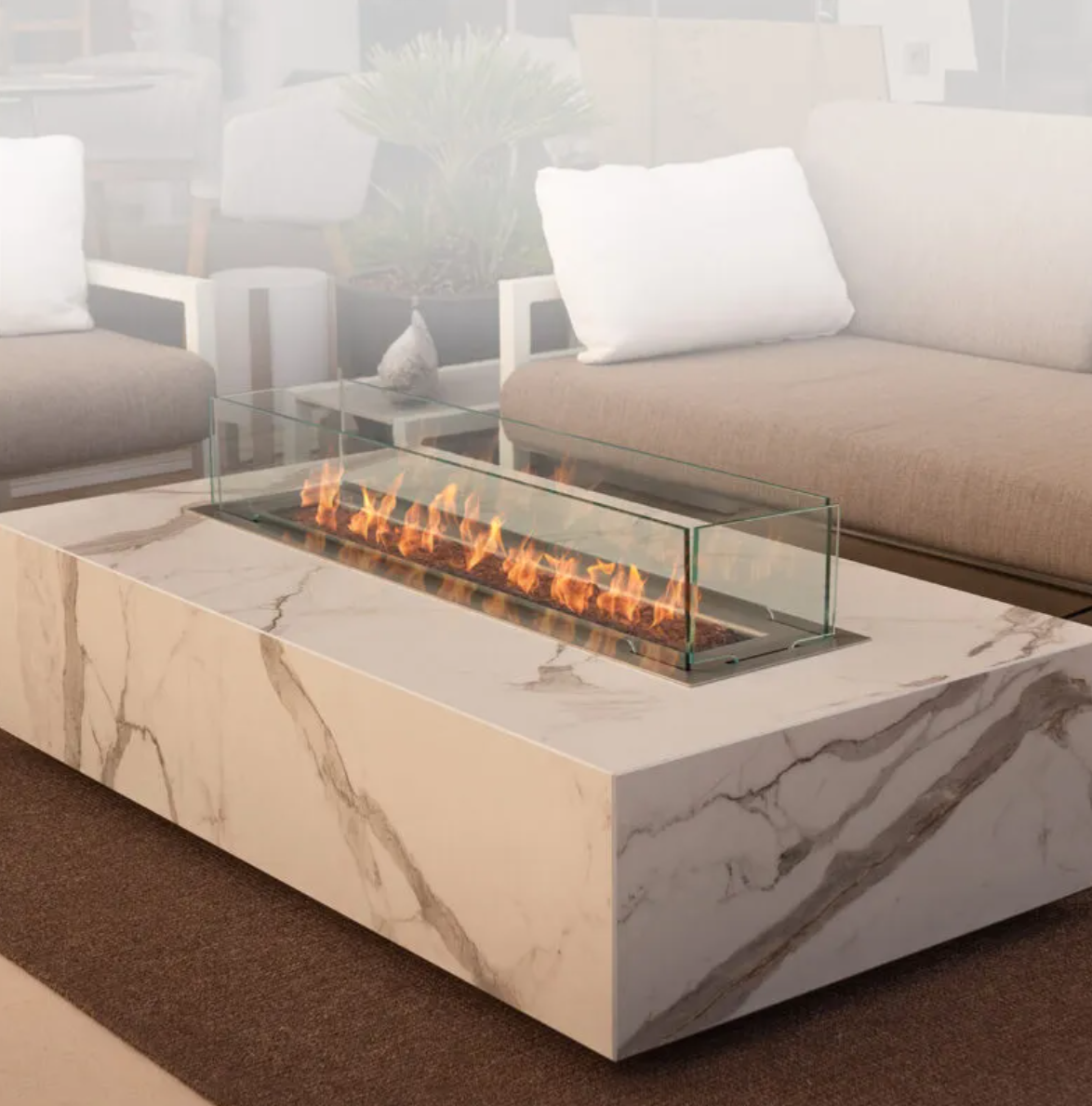 Living room with a modern marble coffee table, a glass fireplace, and beige sofas with white pillows.