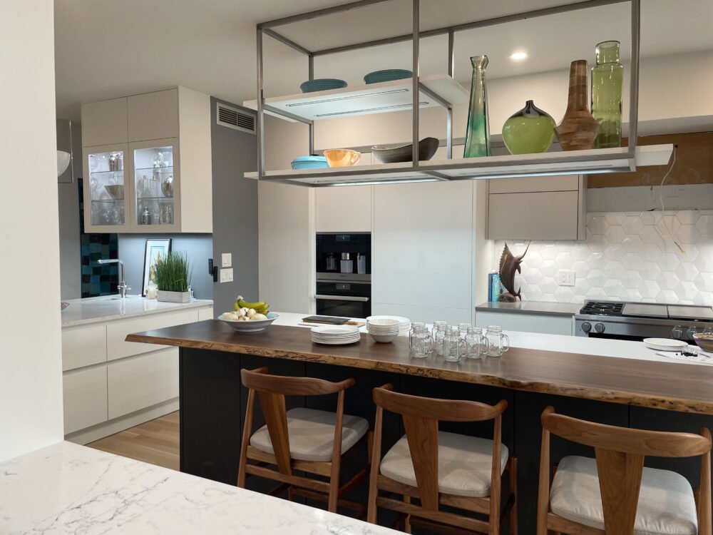 Modern kitchen with a wooden island, glassware, decorative vases, and open shelving with dishes and decorative items.