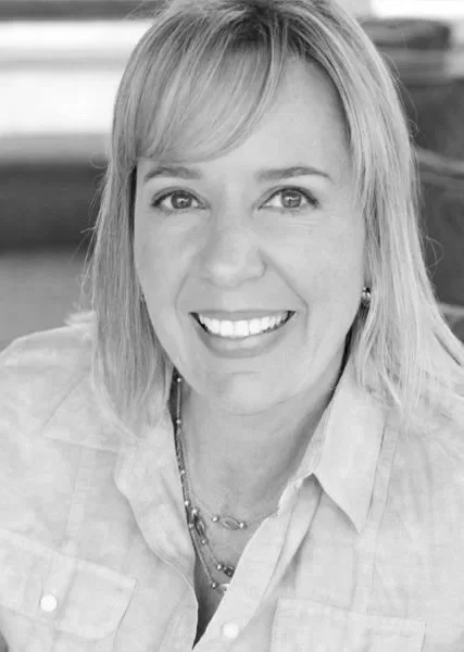 Black and white photo of a woman with light-colored hair, smiling at the camera.