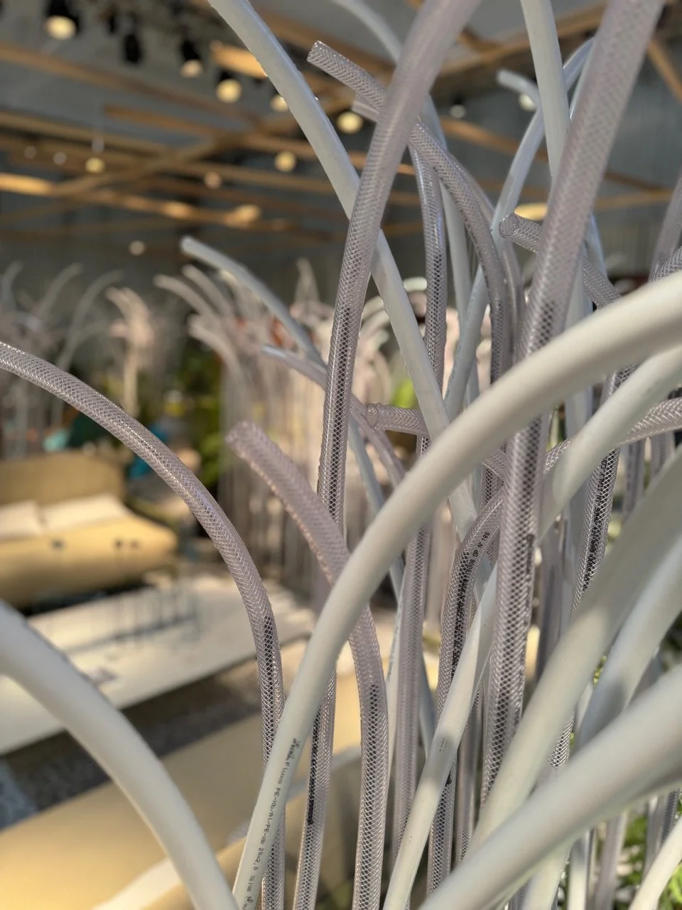 Close-up of tangled white and semi-transparent plastic or rubber tubes or hoses inside a metallic frame or structure.