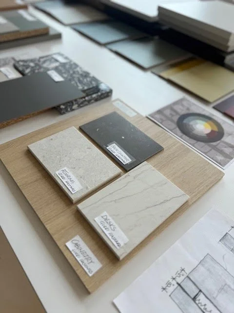 Sample tiles and color palette swatches on a desk with design sketches and color wheels.