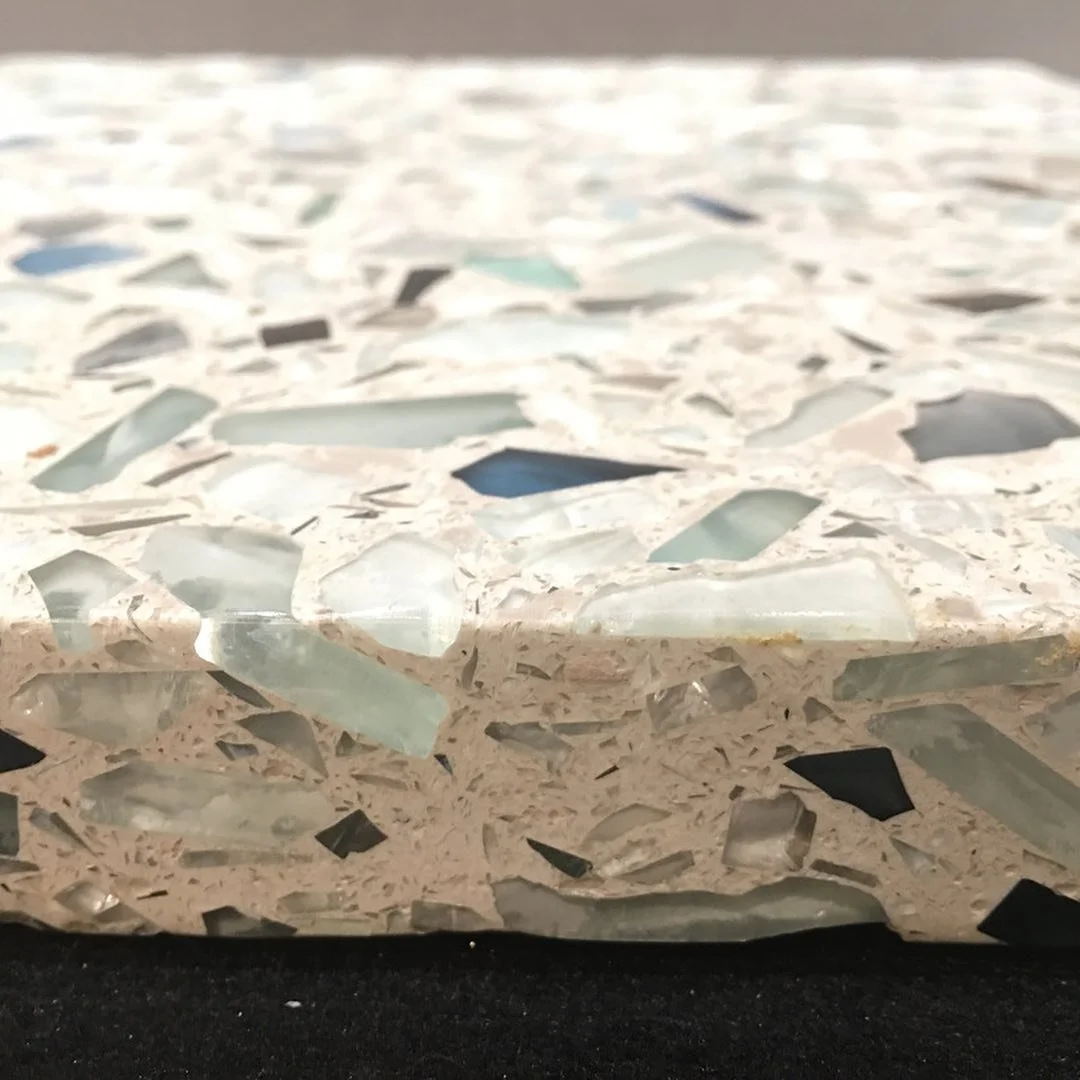 Close-up of a terrazzo countertop with a mixture of white, clear, black, and greenish marble chips.