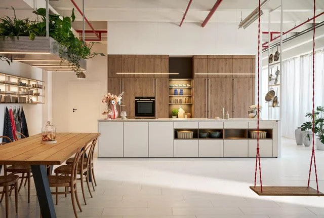 Modern open kitchen with wooden cabinets, white lower cabinets, a dining table with chairs, hanging plants, and a wooden swing in a bright space.