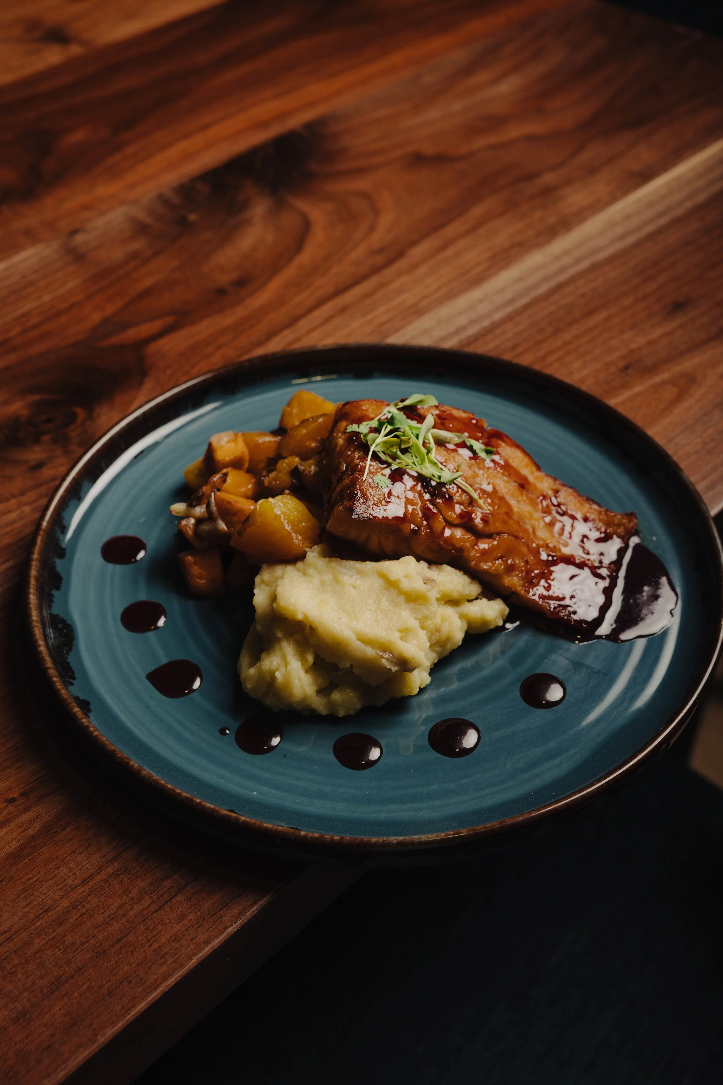 Cedar Plank Salmon featuring roasted salmon, pomegranate glaze, roasted root vegetable sauté, garlic whipped potatoes