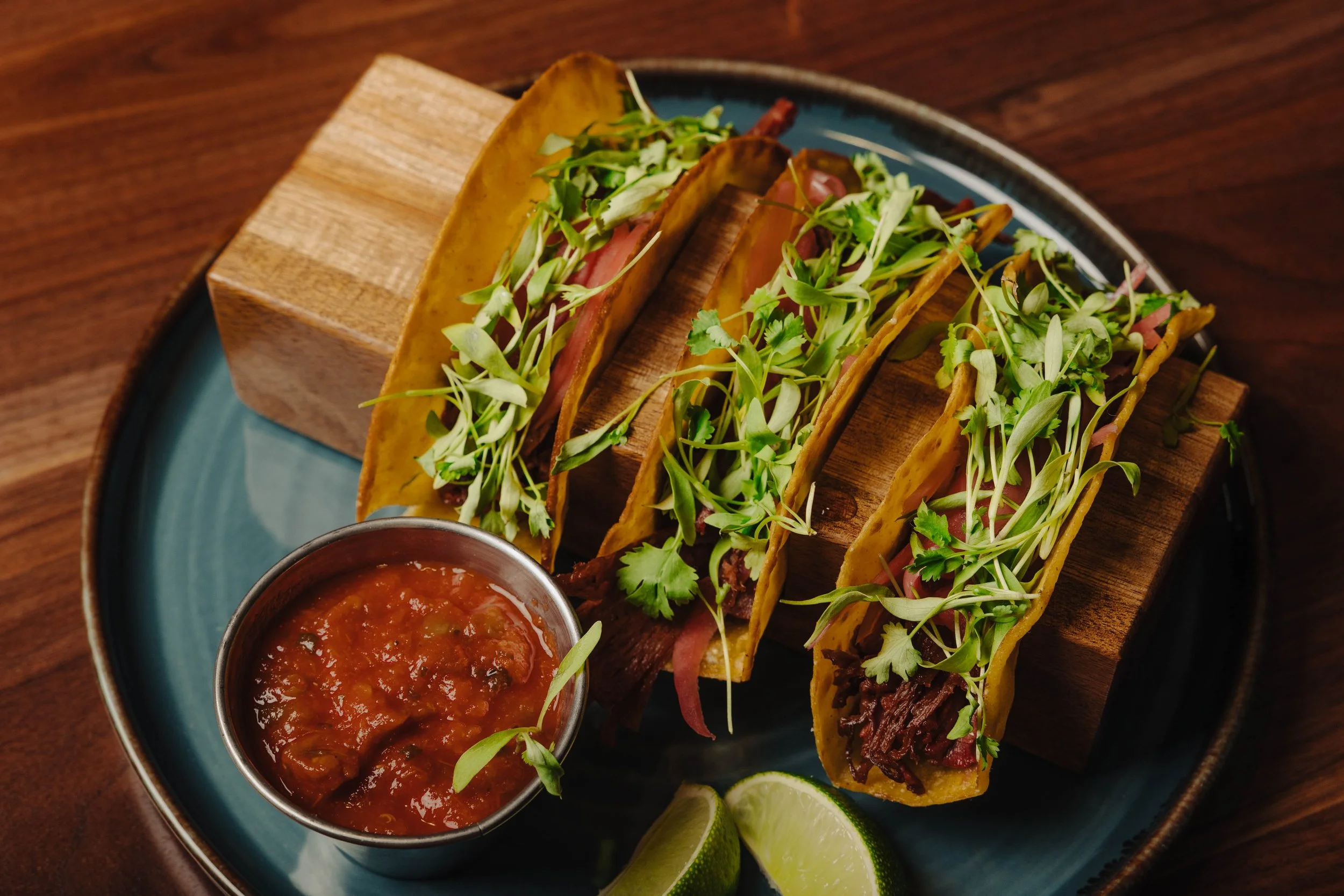Carnitas Quesa Birria featuring pork shoulder, Modelo, pickled red onion, cotija, lime, cilantro, consommé, tortillas
