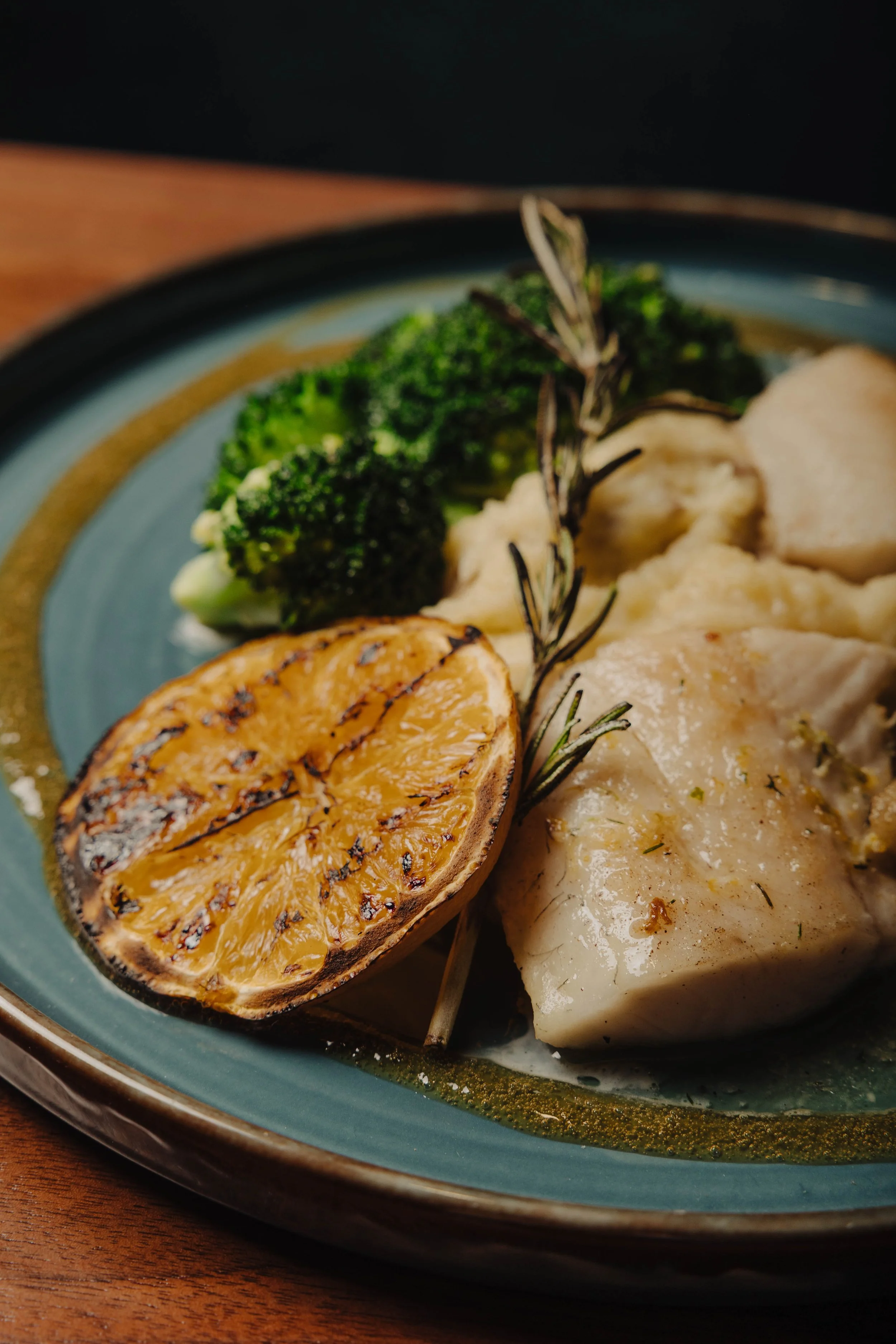 Kindred Walleye featuring seared walleye, garlic whipped potatoes, sautéed broccoli, grilled orange, toasted rosemary