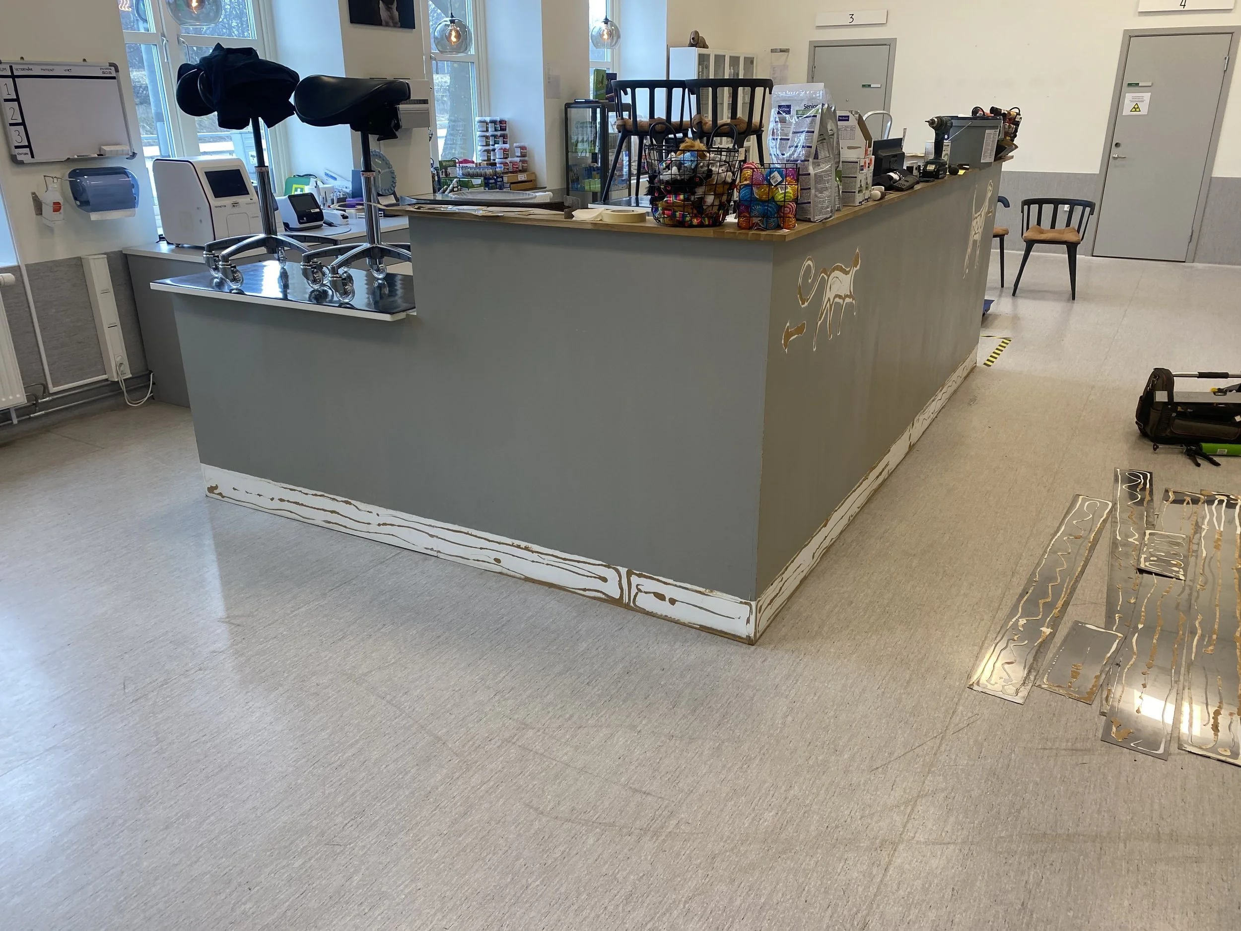 Interiör av en arbetsplatsdisk med verktyg, småprylar, och kontorsutrustning, samt en vägghylla och ett fönster.