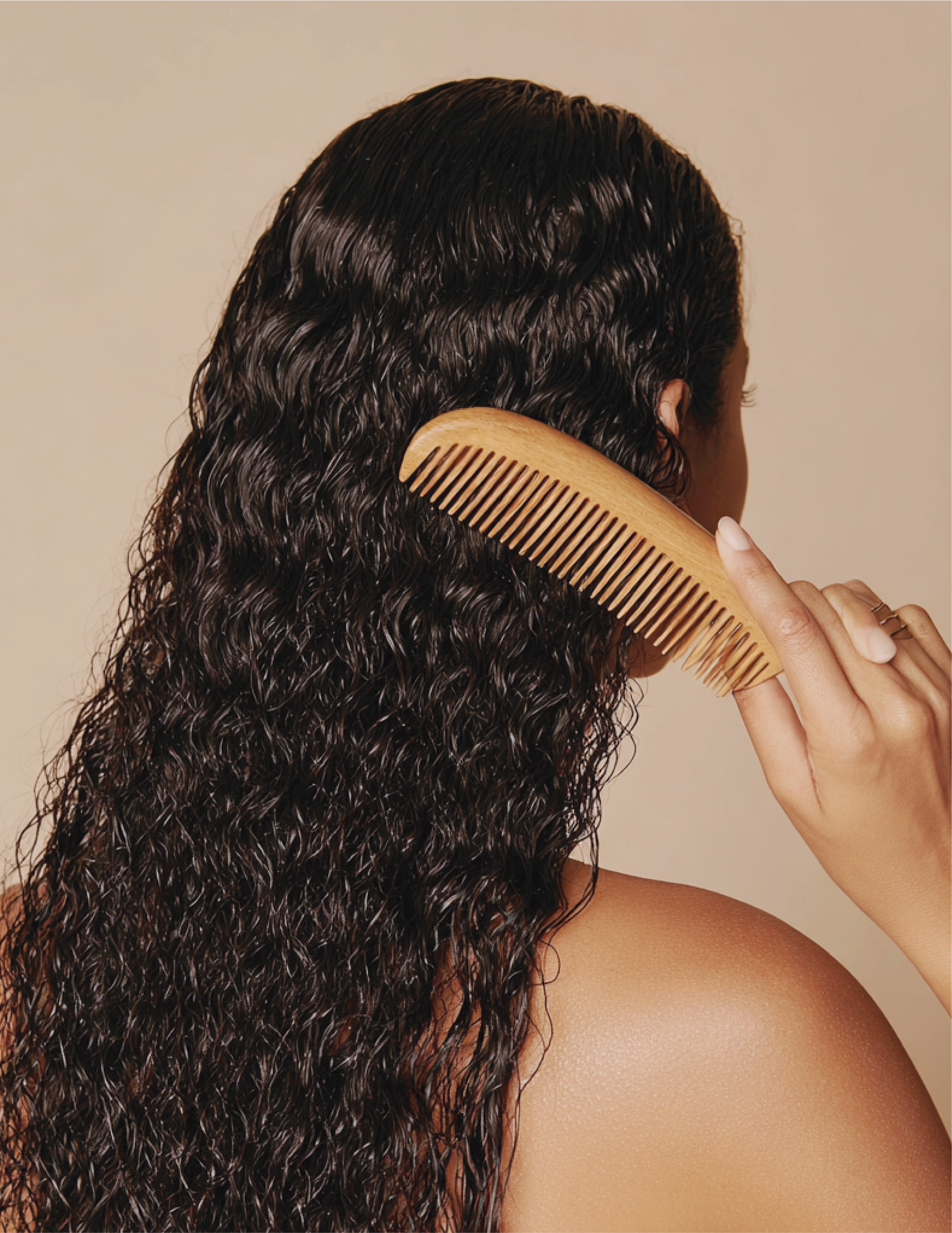 Woman with long, curly dark hair after receiving antidandruff treatment at aan Hair Spa in Roma Norte / Condesa in CDMX. Mujer con cabello largo, rizado y oscuro, cepillándose con un peine de madera después de recibir un tratamiento anticaspa en AAN.