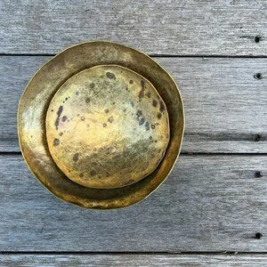 An empty, round, metallic bowl with a smaller bowl inside, placed on a wooden surface.