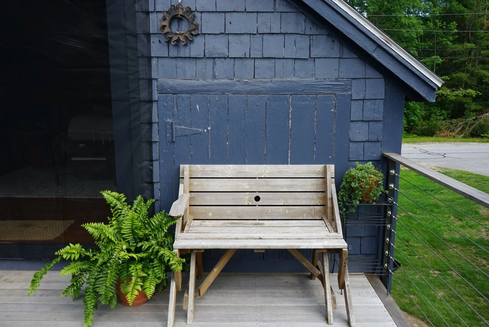 Wooden bench surrounded by outdoor house plants coastal maine
