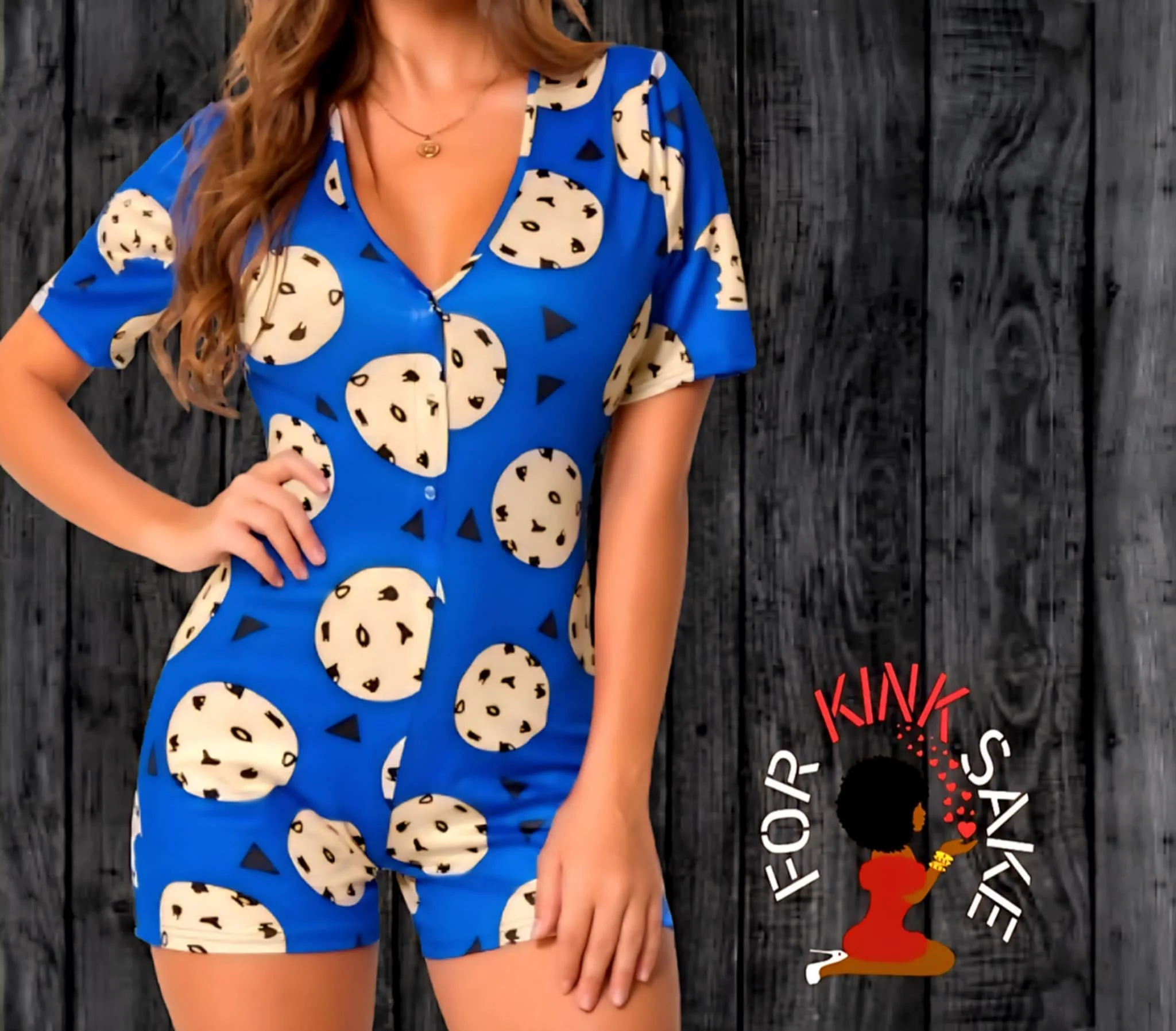 A woman wearing a blue jumpsuit with a leopard print and black triangle pattern, standing against a dark wood background.