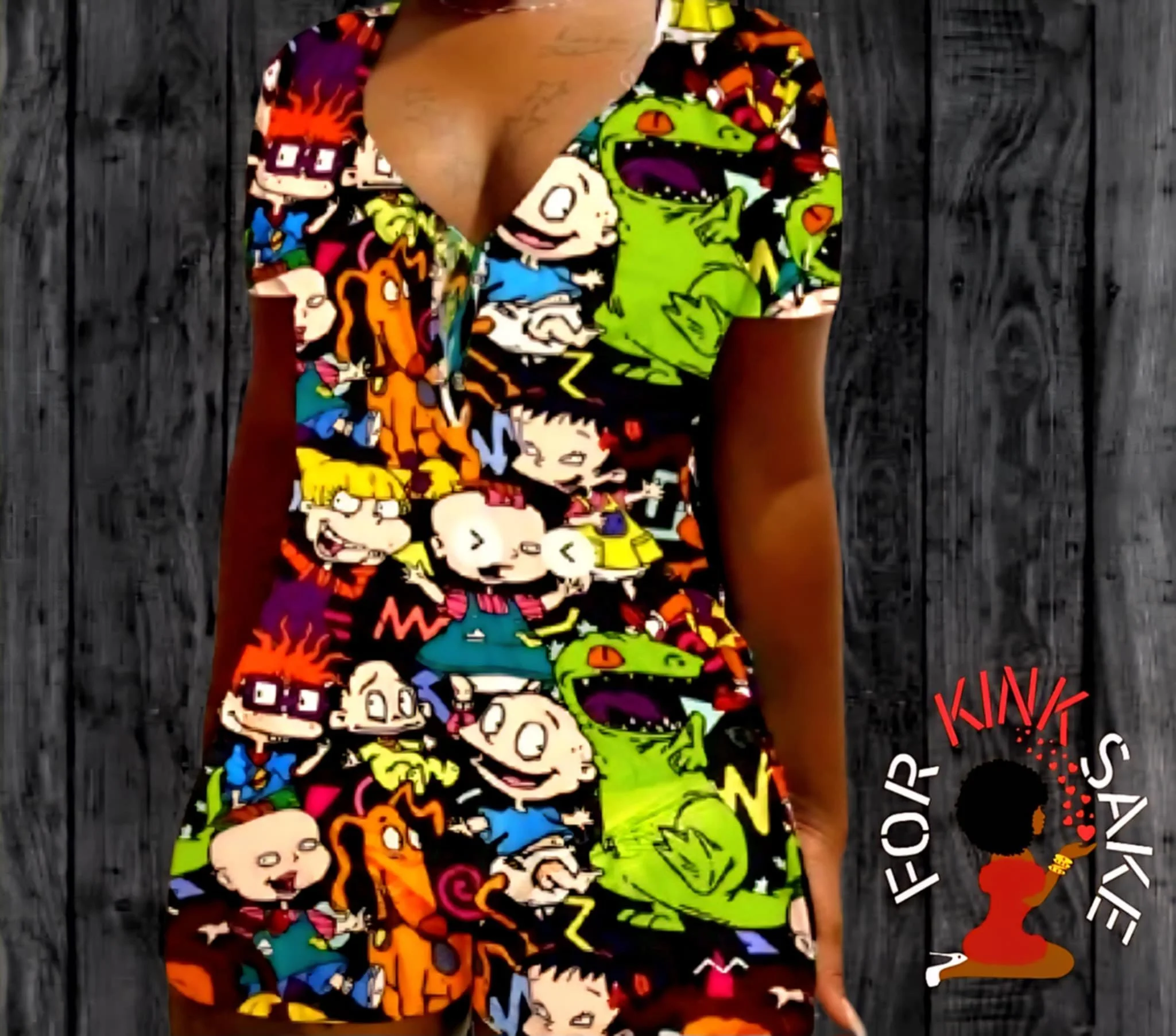 Colorful dress featuring cartoon characters from various shows, including a green dinosaur and characters with glasses, laid on a dark wood surface.