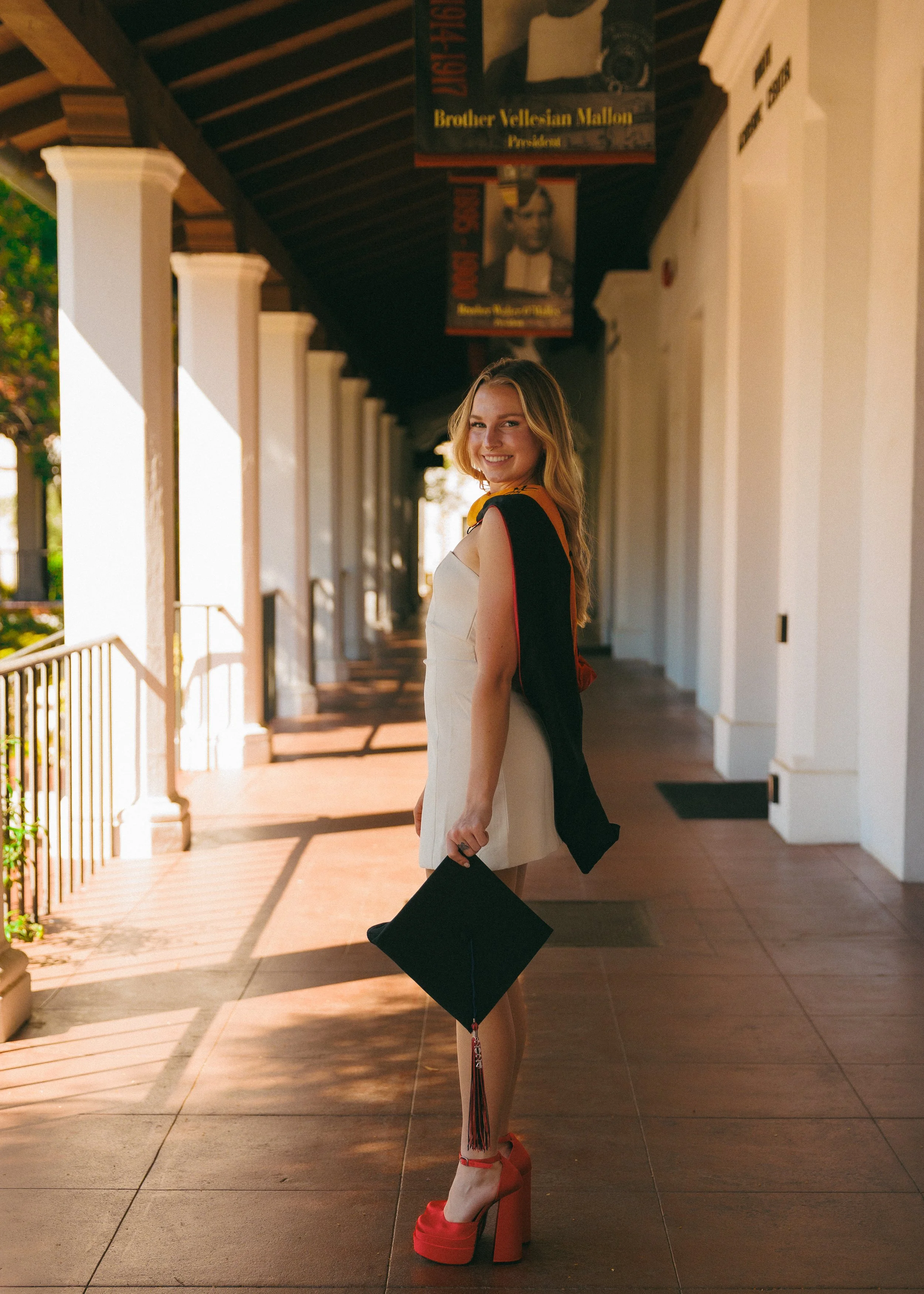 Southern California college graduation photoshoot of a senior in cap and gown on campus, showcasing natural golden hour portrait photography.